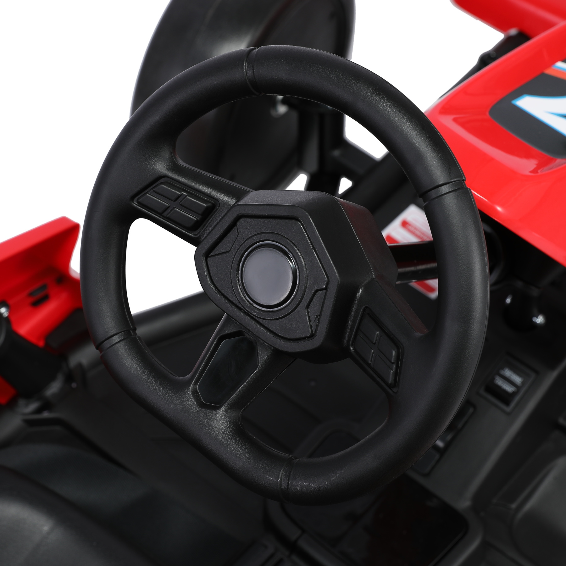 Nahaufnahme eines schwarzen Lenkrads auf einem roten Spielzeugauto. Knöpfe und ein zentrales Emblem sind sichtbar.