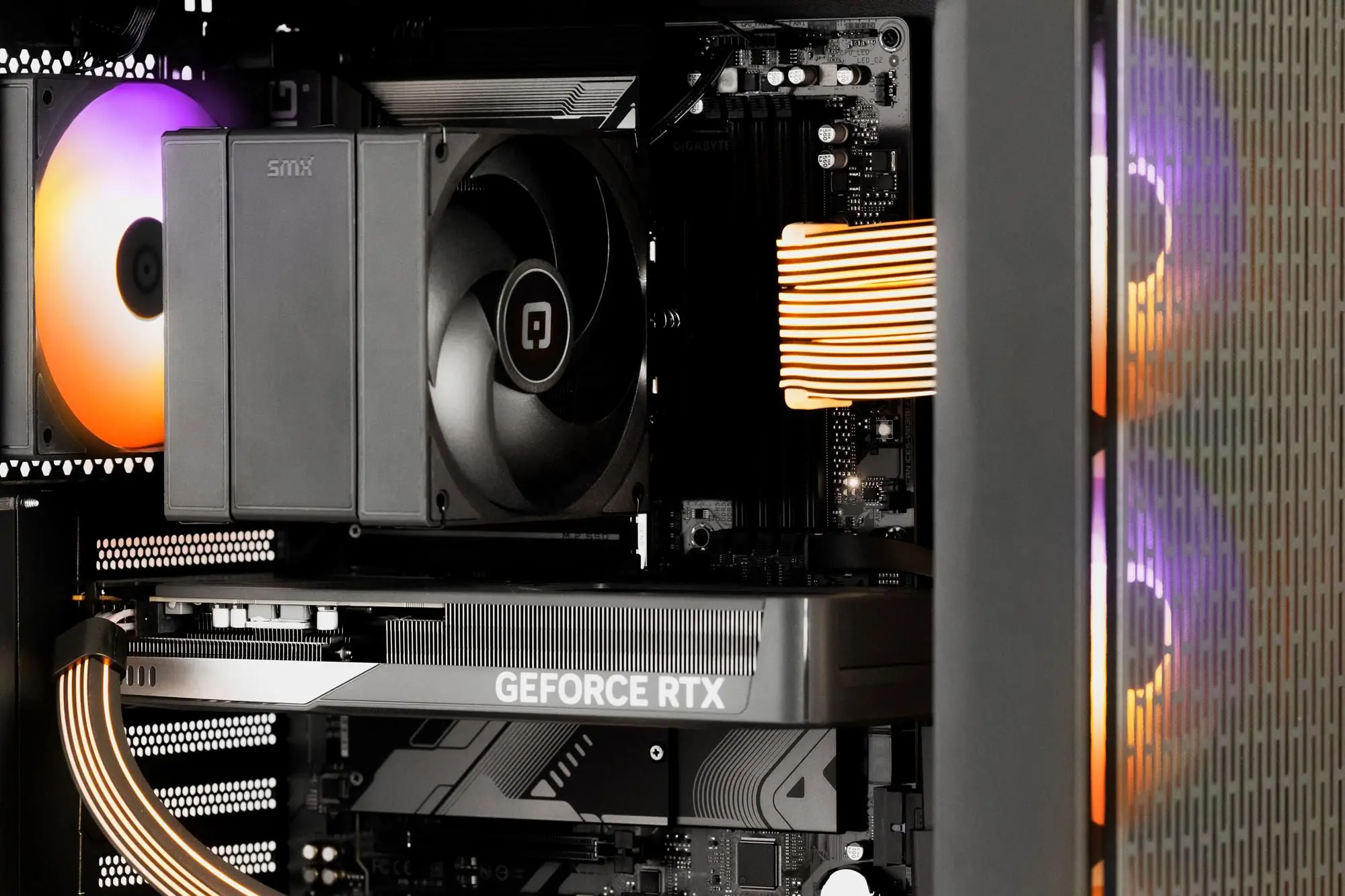 Im Inneren eines Computergehäuses sind ein CPU-Kühler und eine GPU zu sehen. Lüfter mit RGB-Beleuchtung sorgen für farbige Akzente.