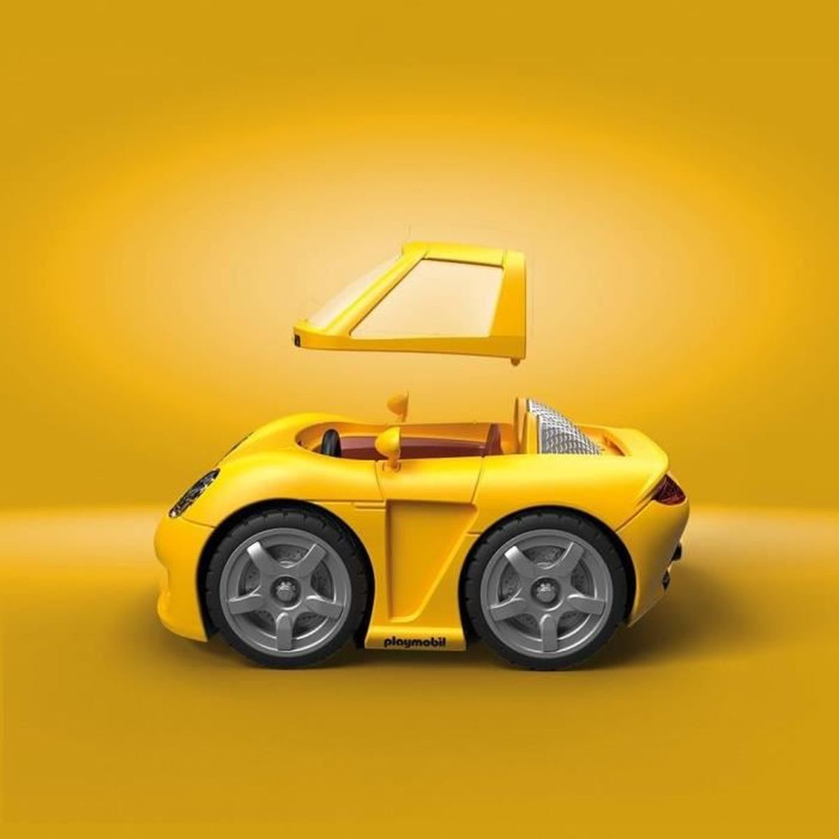 Un coche de juguete amarillo con techo desmontado. El coche tiene ruedas grises y está sobre un fondo amarillo. El techo está encima del coche.