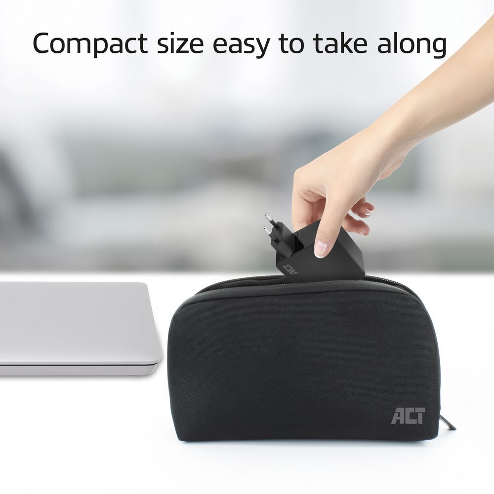 Eine Hand legt ein schwarzes Ladegerät in eine schwarze Tasche. Links ist ein Laptop. Text: Kompakte Größe, leicht mitzunehmen.