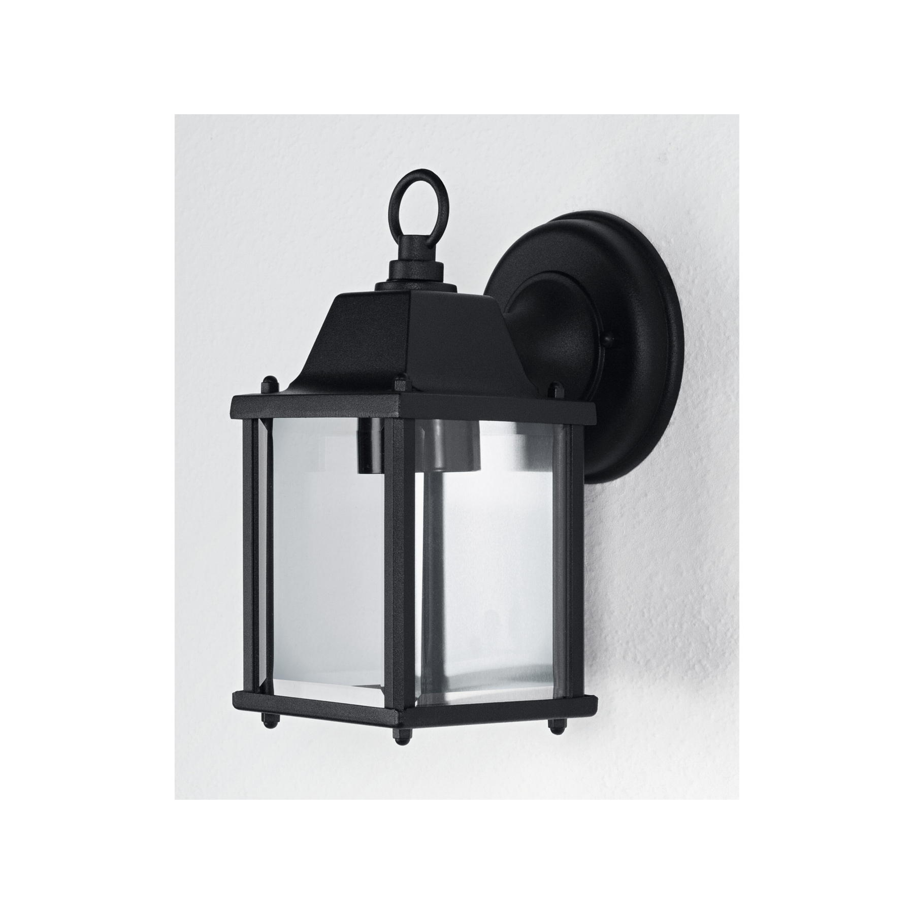 Eine schwarze Außenlaterne ist an einer weißen strukturierten Wand befestigt. Sie hat ein quadratisches Glasgehäuse und eine runde Oberseite.