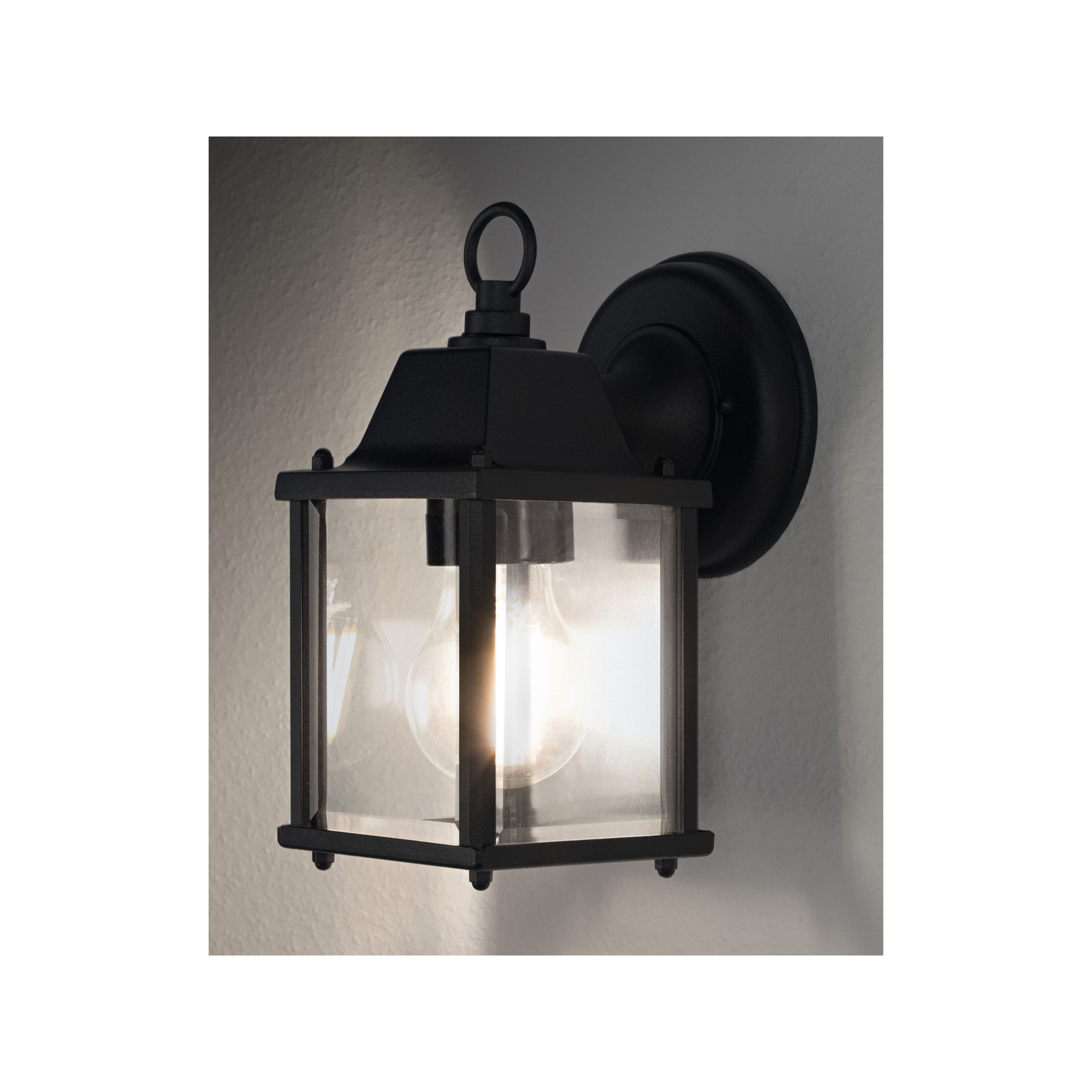 Eine schwarze Außenleuchte mit Glasgehäuse. Das Licht ist an und beleuchtet das Innere.