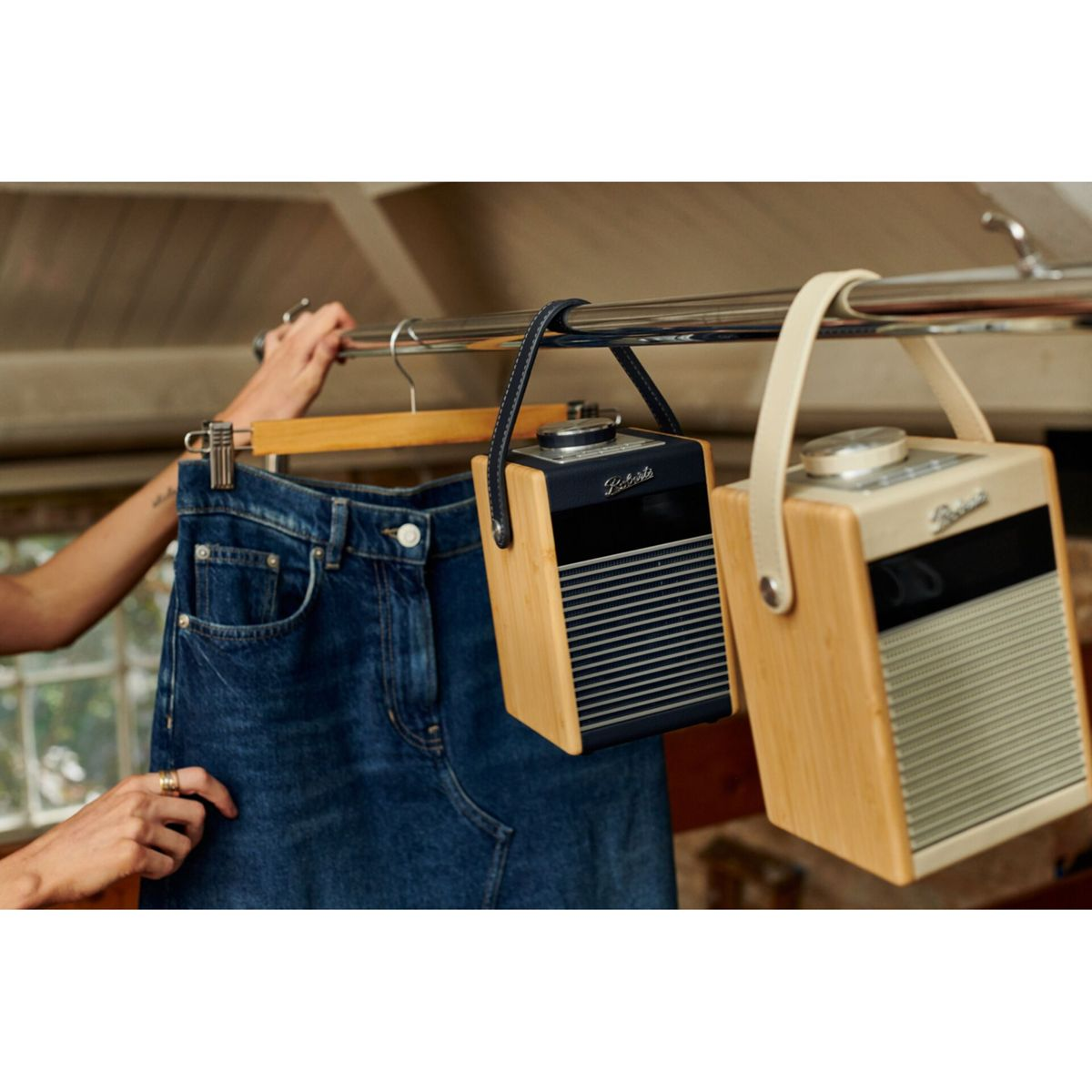 Una persona appende una gonna di jeans a un'asta, accanto a due radio di legno con manici in pelle.