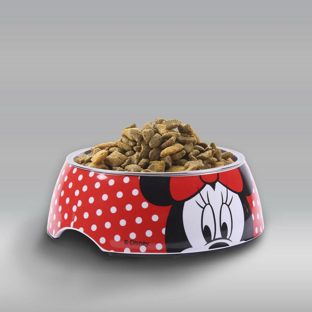 Una ciotola per animali domestici di Minnie Mouse piena di crocchette marroni. La ciotola è rossa con pois bianchi e un volto di Minnie.