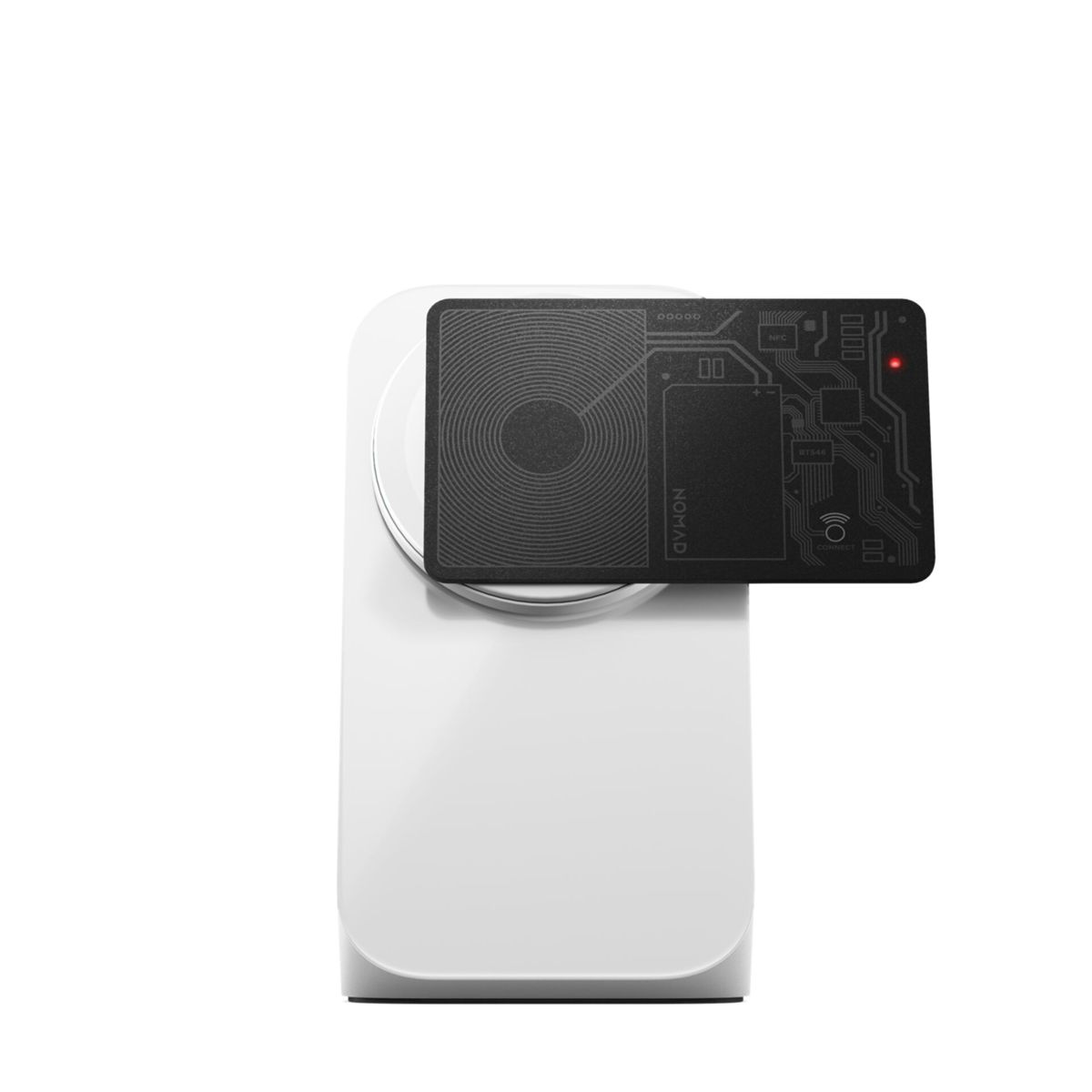 Una carta nera con design a circuito è posizionata su un caricatore wireless bianco, con luce rossa.