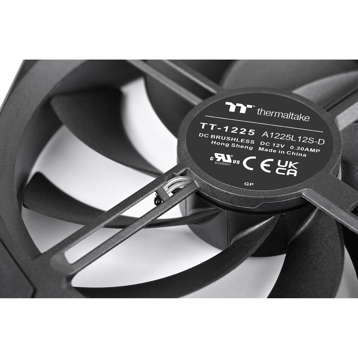 Primo piano di una ventola per computer nera con pale curve. Al centro un'etichetta con testo e loghi, tra cui 'thermaltake'.