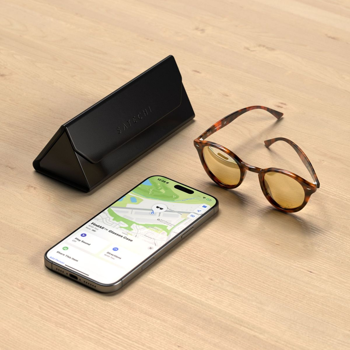 Ein Telefon, eine Brille und ein Etui liegen auf Holz. Das Telefon zeigt eine Karte an. Die Brille hat Schildpattrahmen. Das Etui ist schwarz und dreieckig.