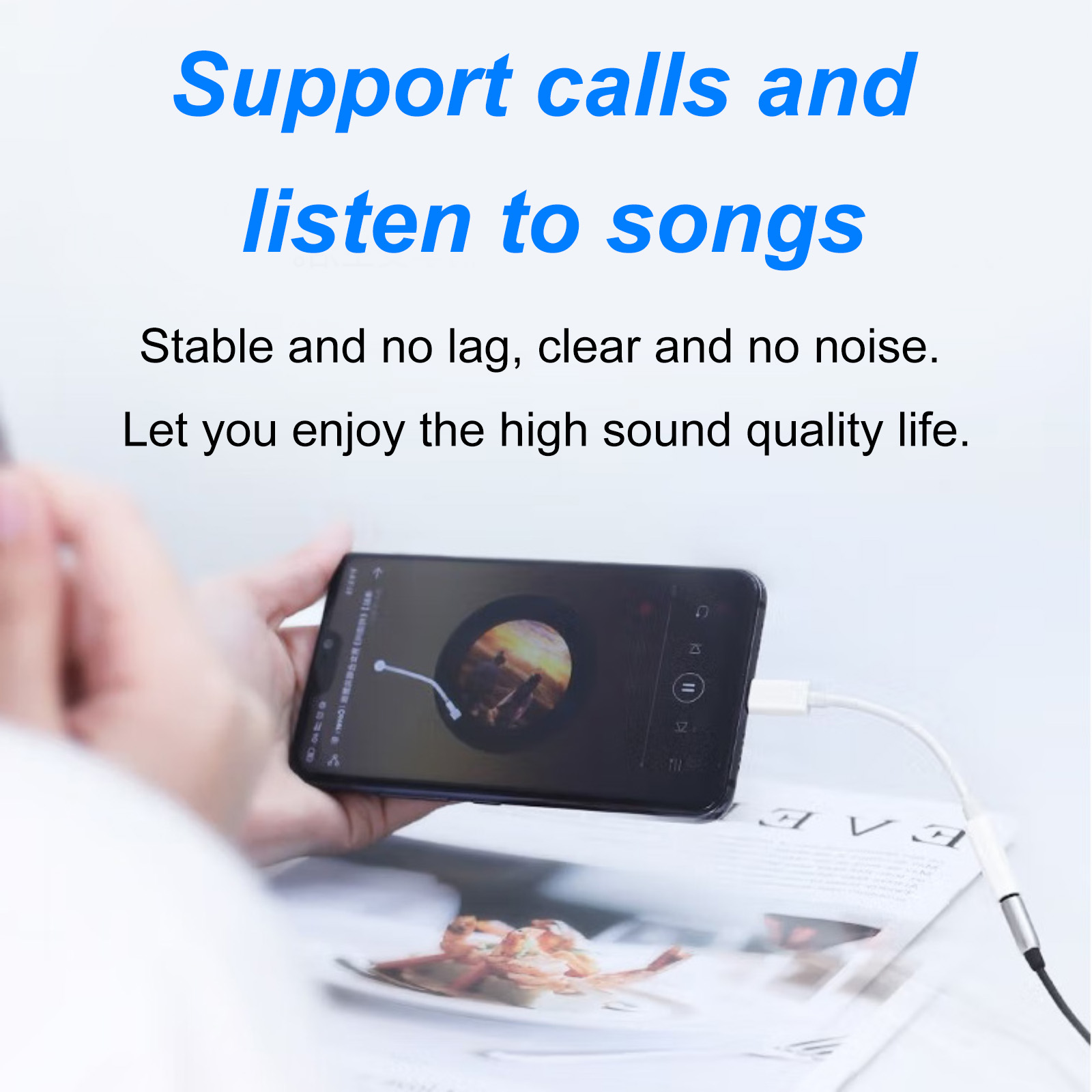 Eine Hand hält ein Telefon, das Musik abspielt, verbunden mit einem weißen Kabel auf einer Zeitschrift, mit Text 'Anrufe unterstützen und Songs hören'.