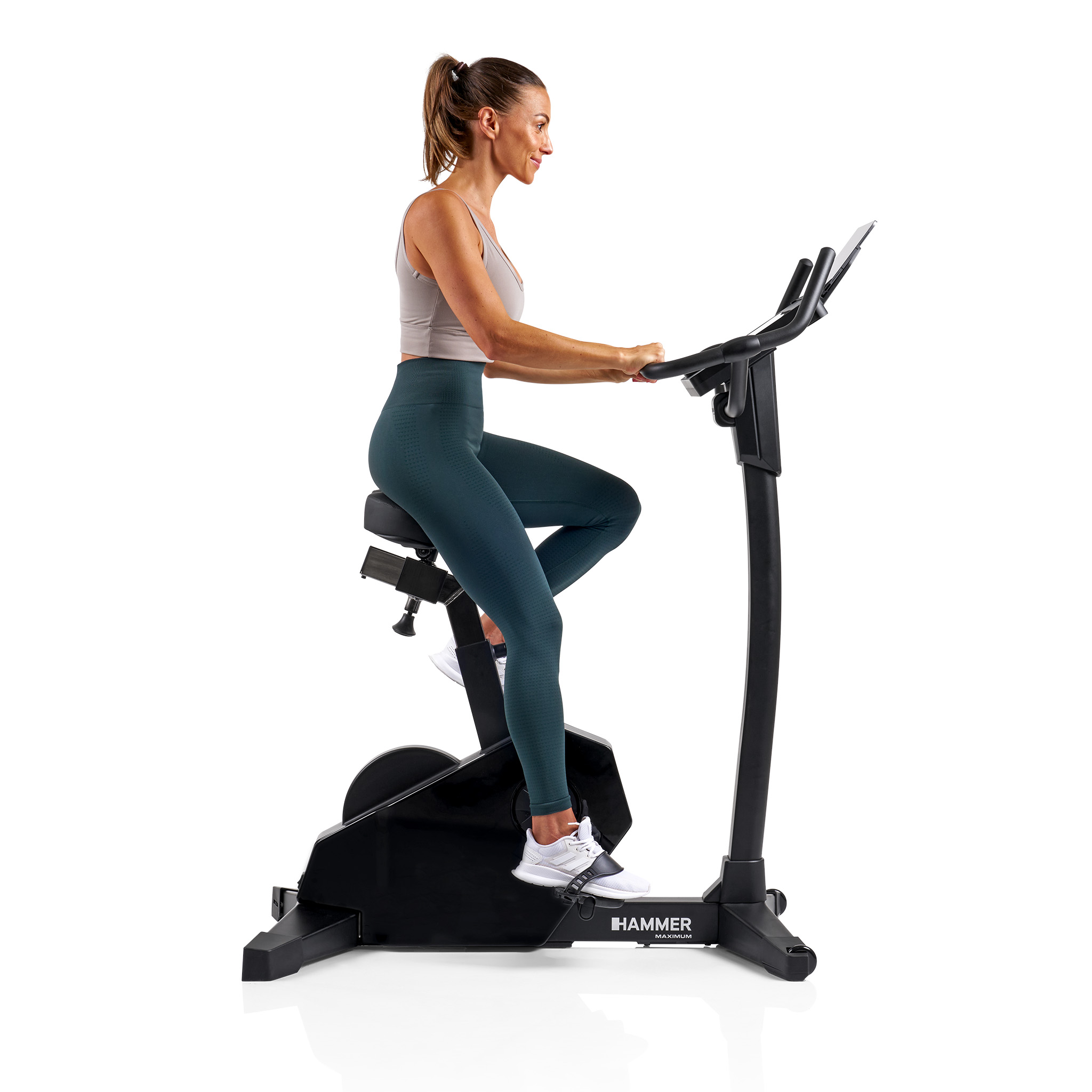 Eine Frau trainiert auf einem Heimtrainer. Sie trägt Sportkleidung. Das Fahrrad ist schwarz.
