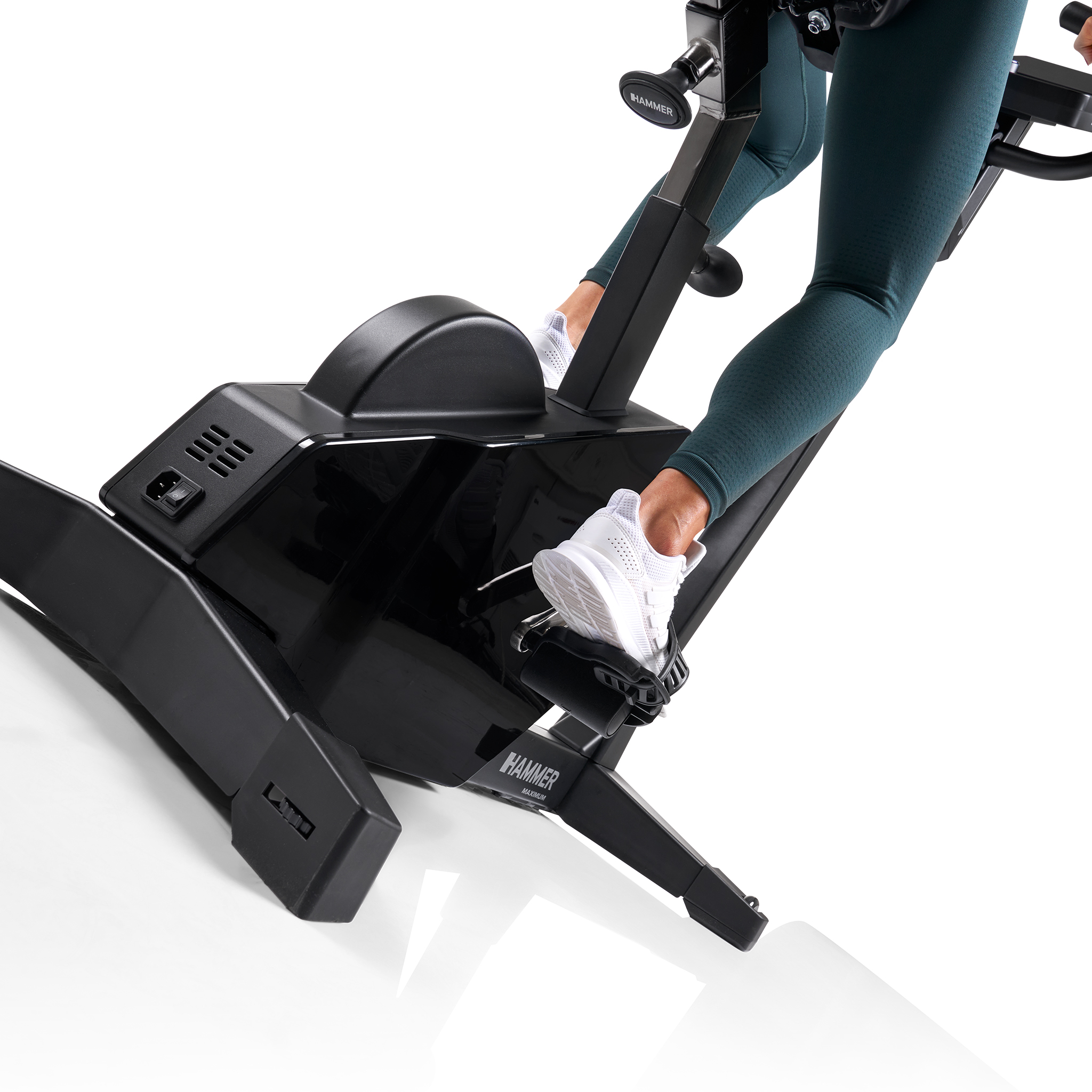 Eine Person auf einem schwarzen Trainingsrad, trägt tealfarbene Leggings und weiße Turnschuhe, auf weißem Hintergrund.