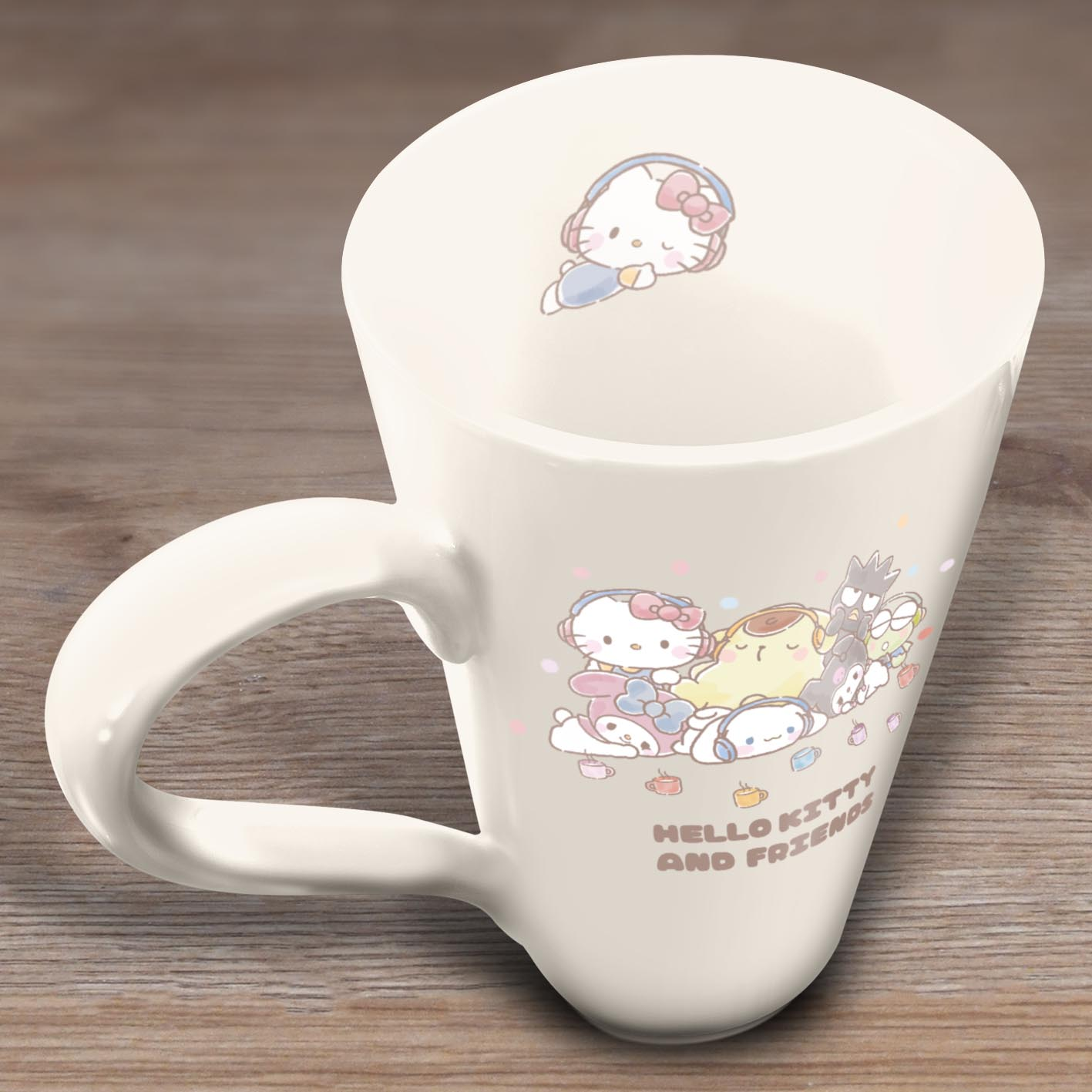 Eine Hello Kitty-Tasse mit Charakteren darauf, die auf einer Holzoberfläche steht. Die Tasse ist weiß und hat einen gebogenen Henkel.