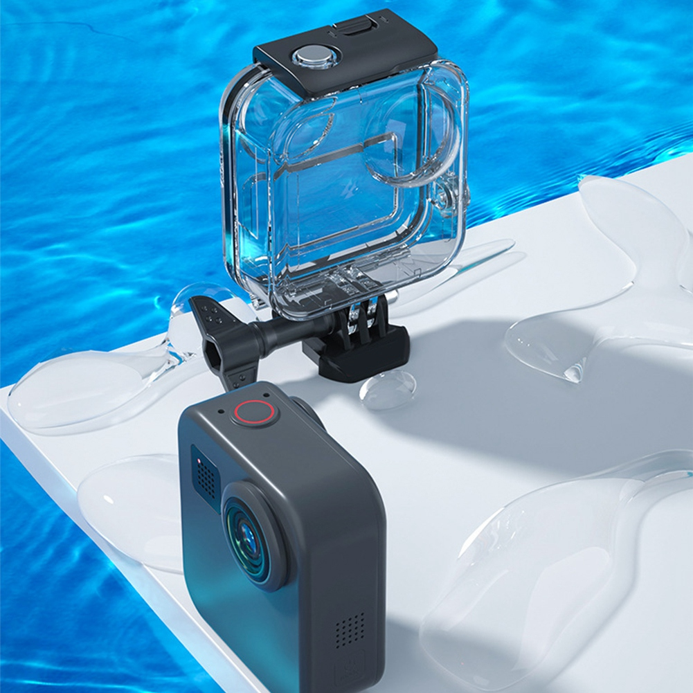 Eine graue Action-Kamera mit einer transparenten wasserdichten Hülle liegt auf einer weißen Oberfläche mit Wassertropfen. Blaues Wasser im Hintergrund.