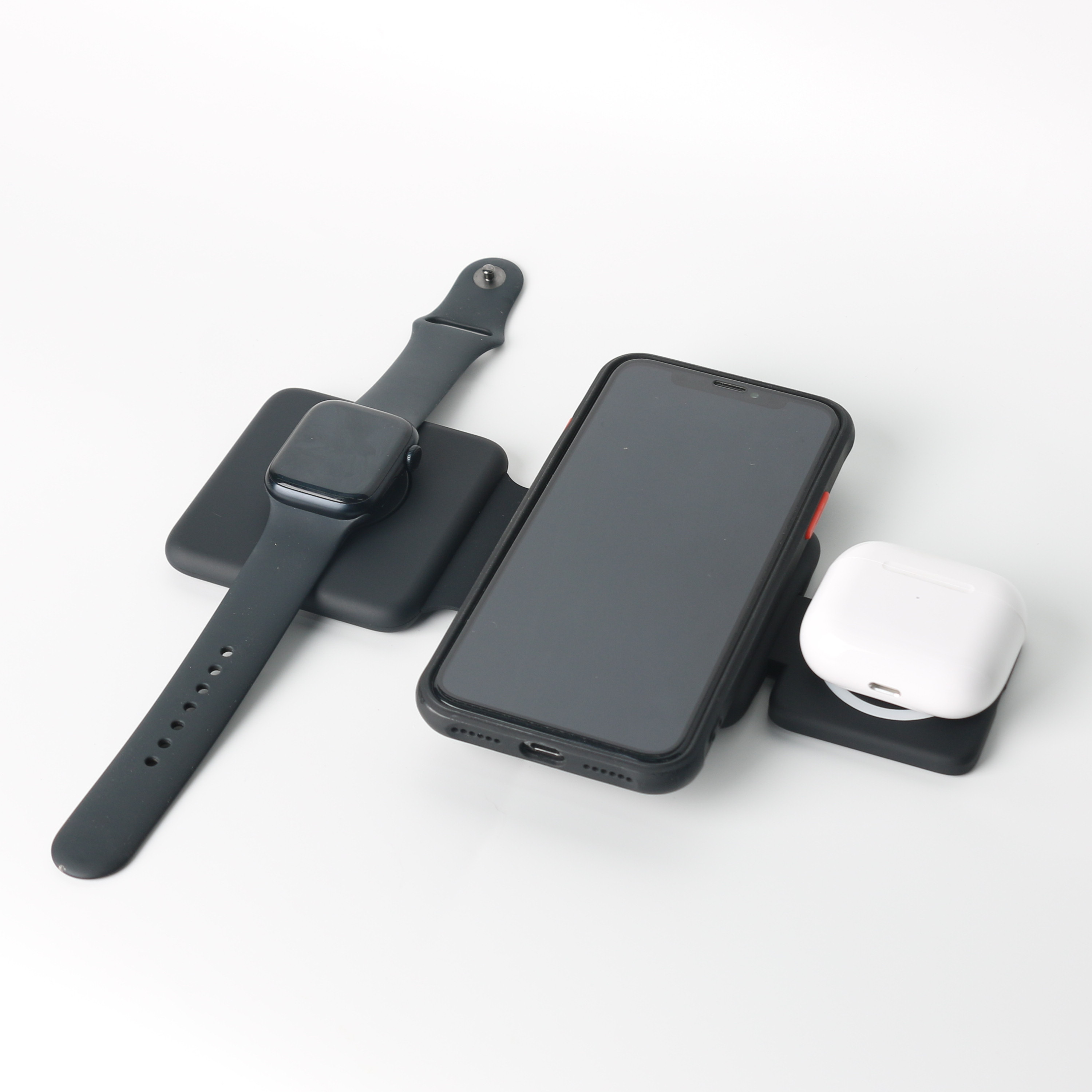 Schwarzes Smartphone, Smartwatch und weiße Ohrhörer auf weißer Oberfläche. Das Telefon hat eine schwarze Hülle.