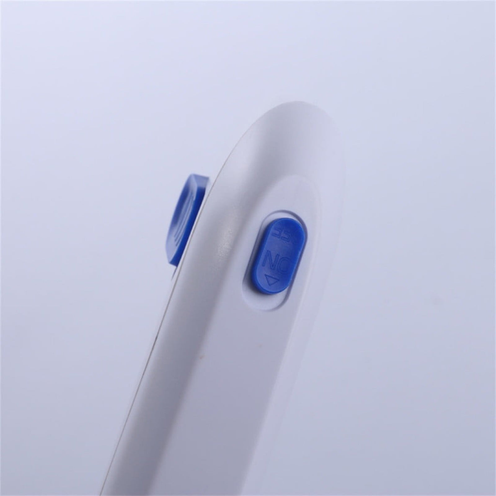 Ein weißes Objekt mit einem blauen Knopf mit der Aufschrift „ON“ auf hellem Hintergrund. Ein weiterer blauer Knopf ist sichtbar.
