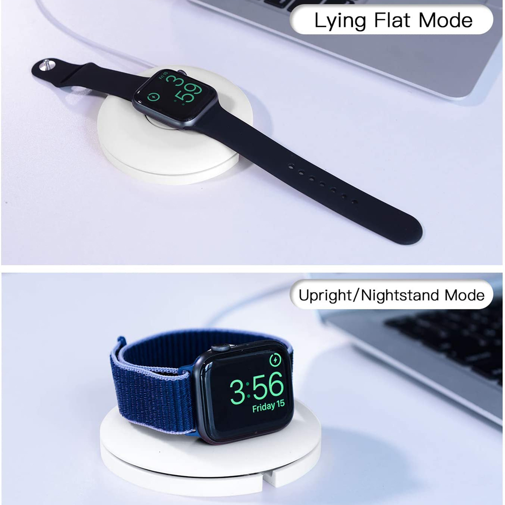 Zwei Apple Watches auf weißen Ladegeräten. Eine flach, die andere aufrecht. Laptops sind im Hintergrund. Die Uhrzeit wird angezeigt.