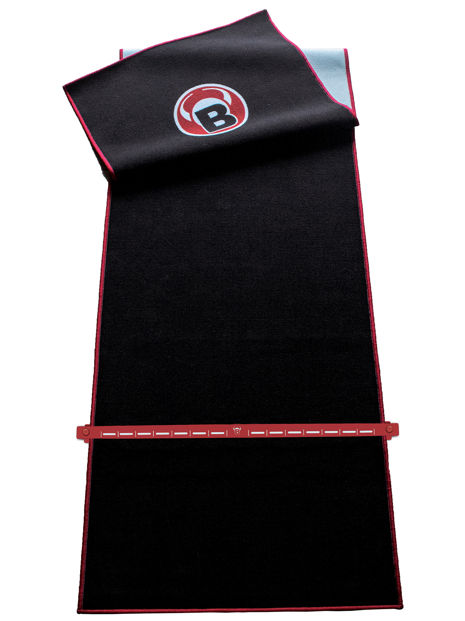Schwarze Matte mit roter Umrandung und Logo, teilweise gerollt. Unten befindet sich ein rotes, linealartiges Objekt mit weißen Markierungen.