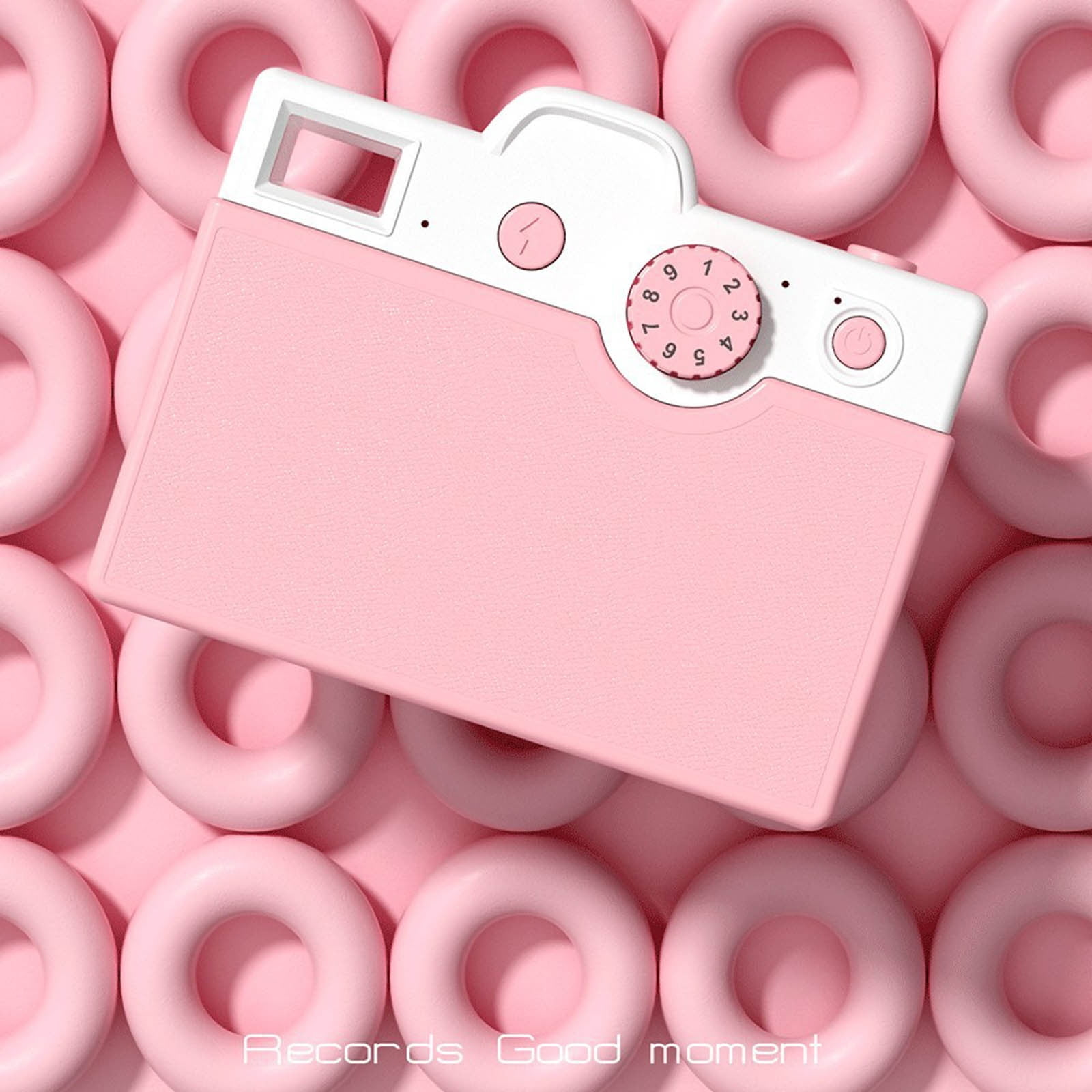 Rosa Spielzeugkamera auf rosa Hintergrund mit rosa Donut-Formen. Weiße Akzente auf der Kamera. Text: Records Good moment.