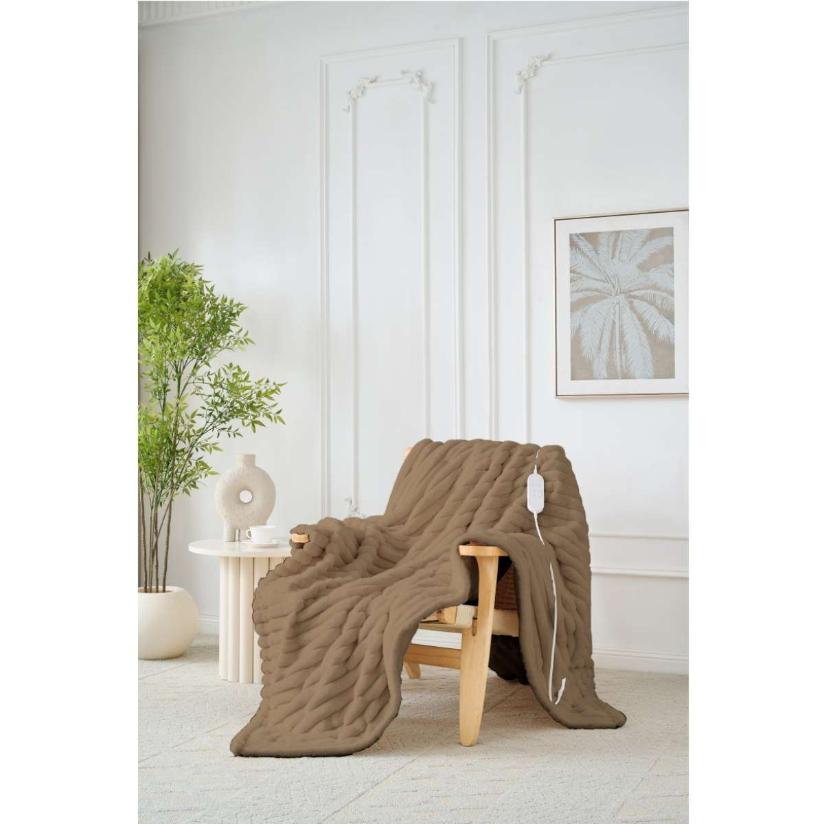 Eine braune Strickdecke liegt über einem Holzstuhl. Ein Netzkabel ist angeschlossen. Eine Pflanze, Vase und ein Bilderrahmen befinden sich im Hintergrund.