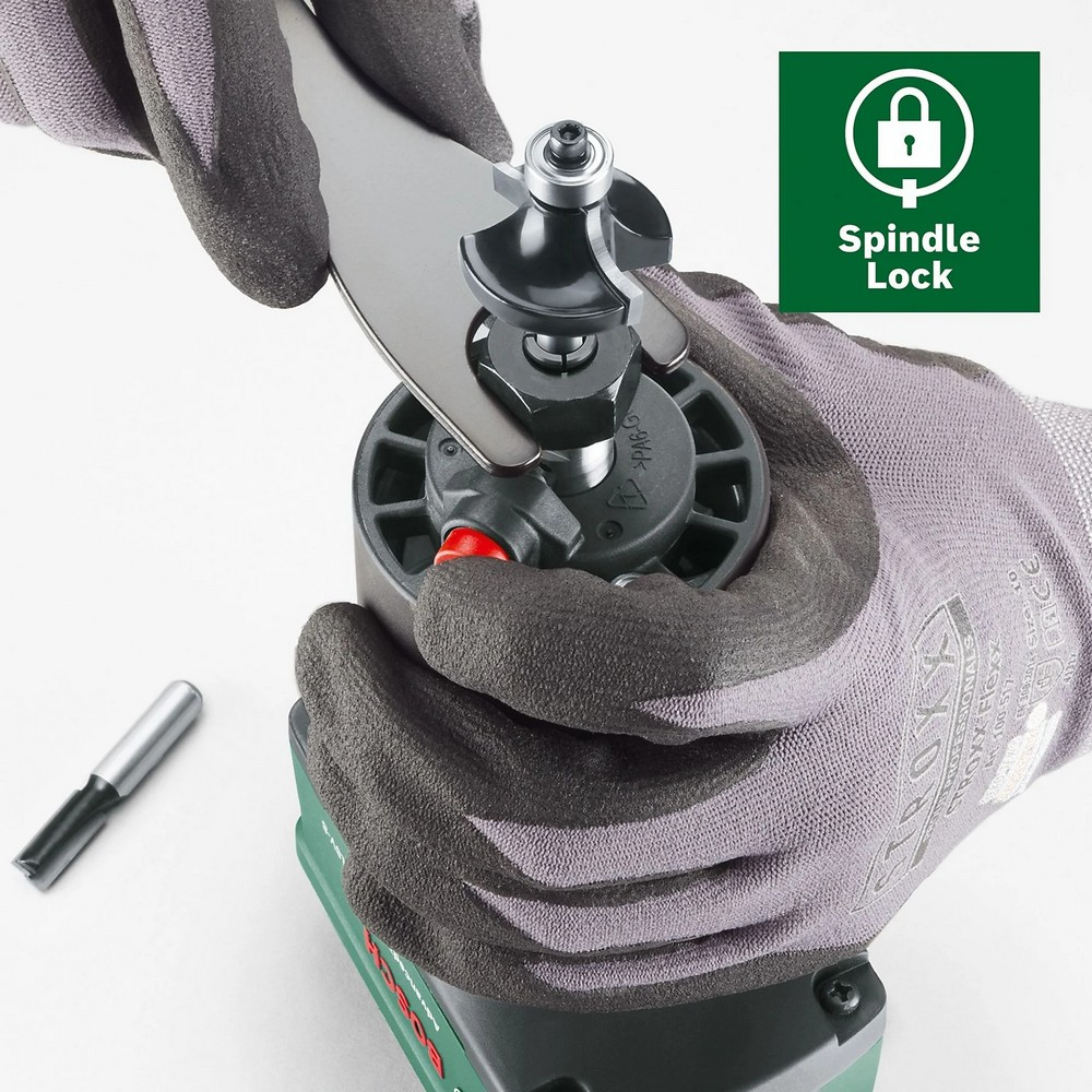 Hände in Handschuhen benutzen einen Schraubenschlüssel an einem Elektrowerkzeug. Ein Bit und ein 'Spindle Lock'-Logo sind ebenfalls sichtbar.