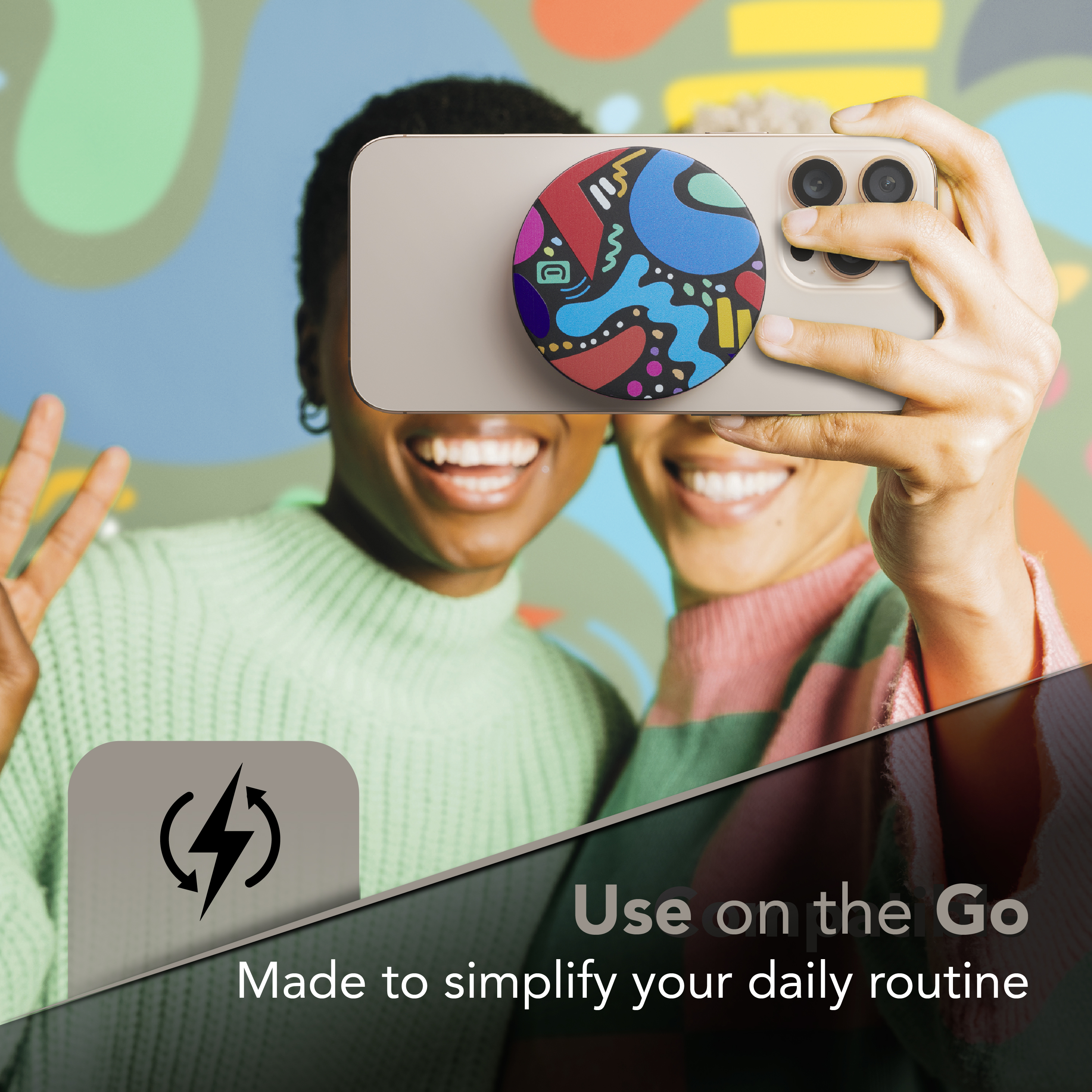 Due donne sorridenti che scattano un selfie con un telefono. Il telefono ha un pop socket con un design colorato.