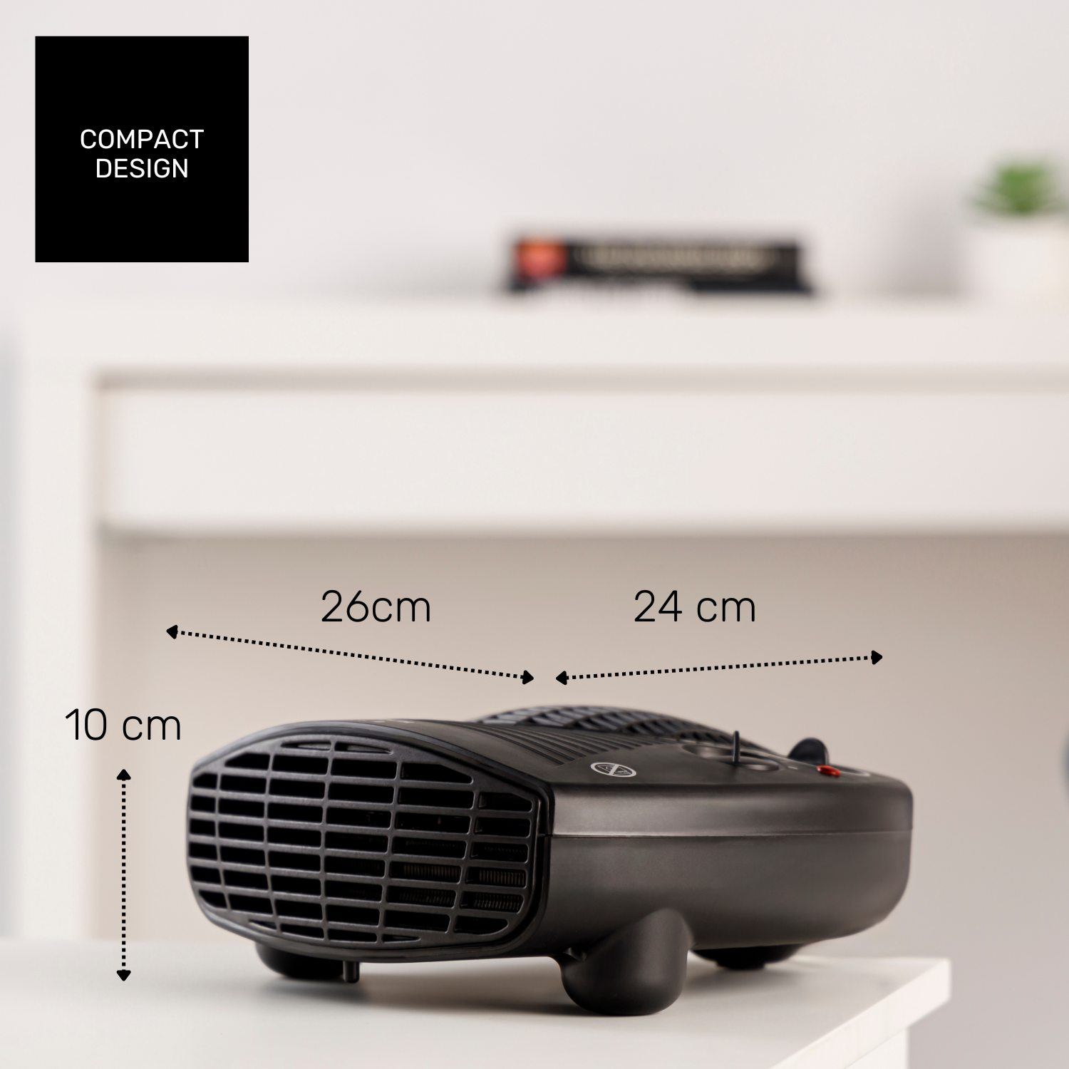 Un calefactor negro y compacto sobre una superficie blanca. Dimensiones: 26 cm, 24 cm y 10 cm. Texto "COMPACT DESIGN" visible.