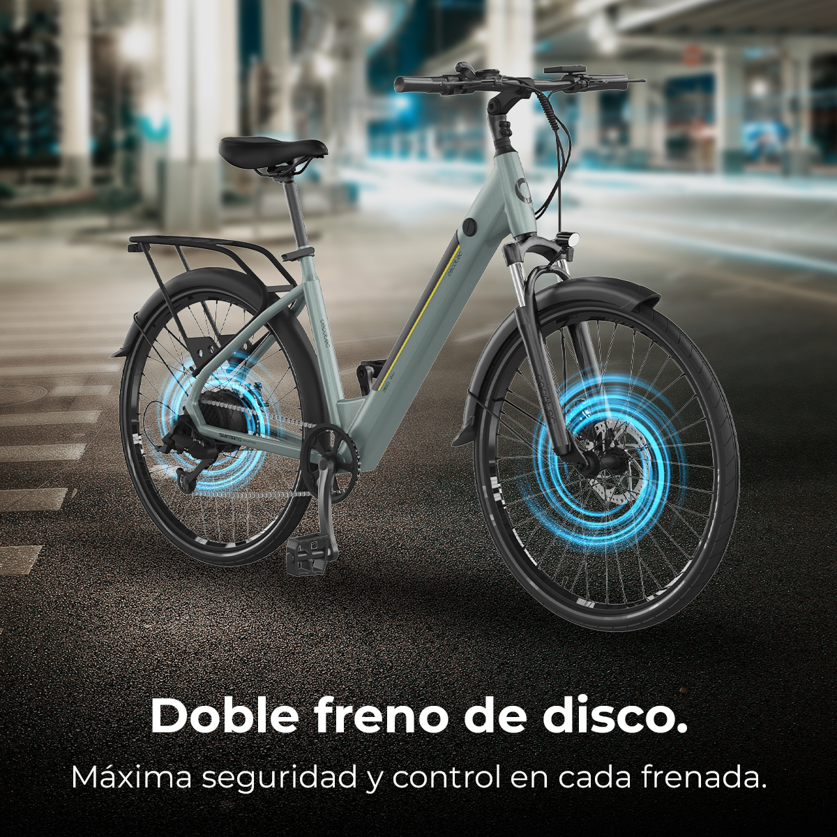 Gezeigt wird ein Elektrofahrrad mit Fokus auf seine Scheibenbremsen. Das Fahrrad ist grau mit schwarzen Reifen, vor unscharfem Stadt-Hintergrund.