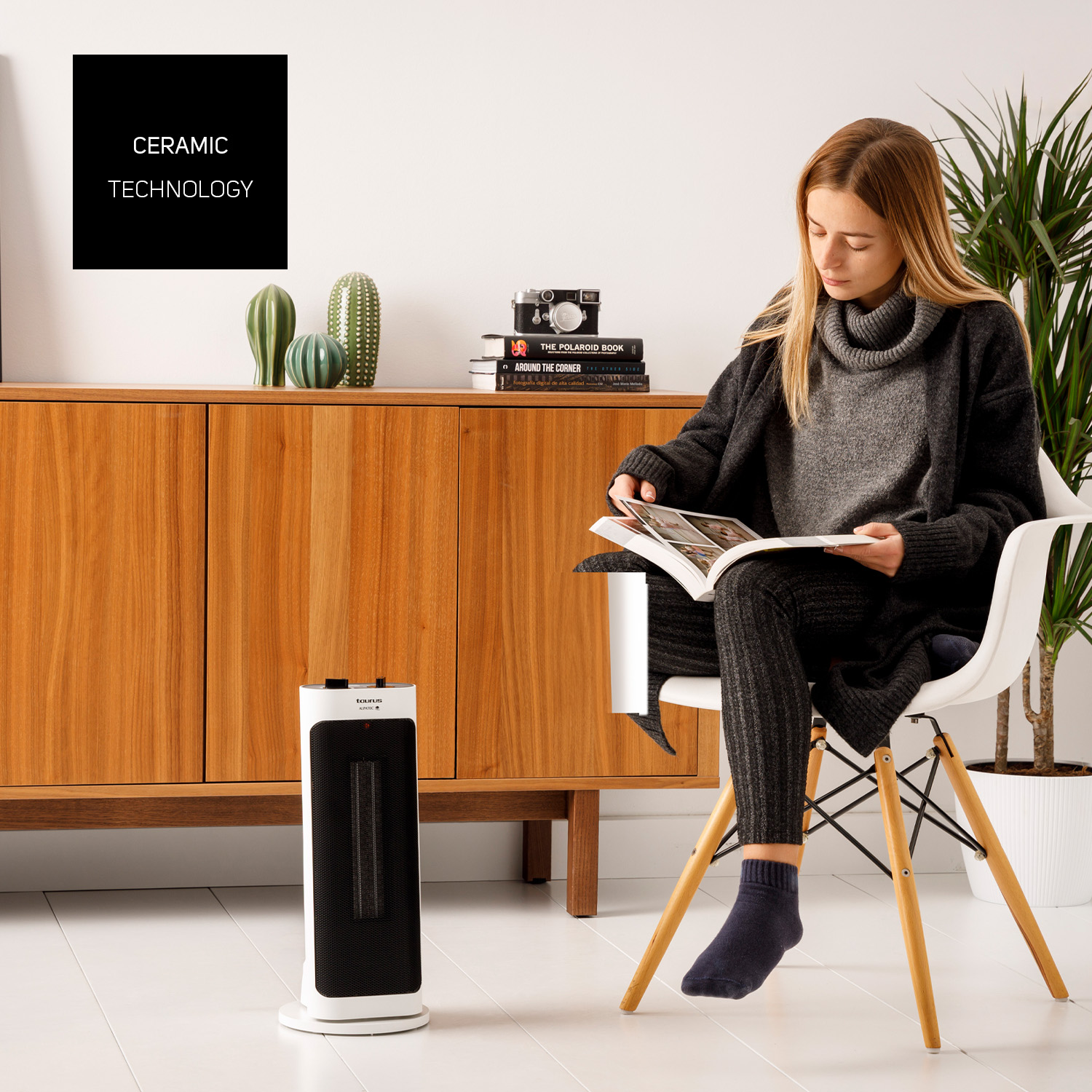 Una donna legge un libro vicino a un termosifone. Un mobile in legno e decorazioni di cactus sullo sfondo.