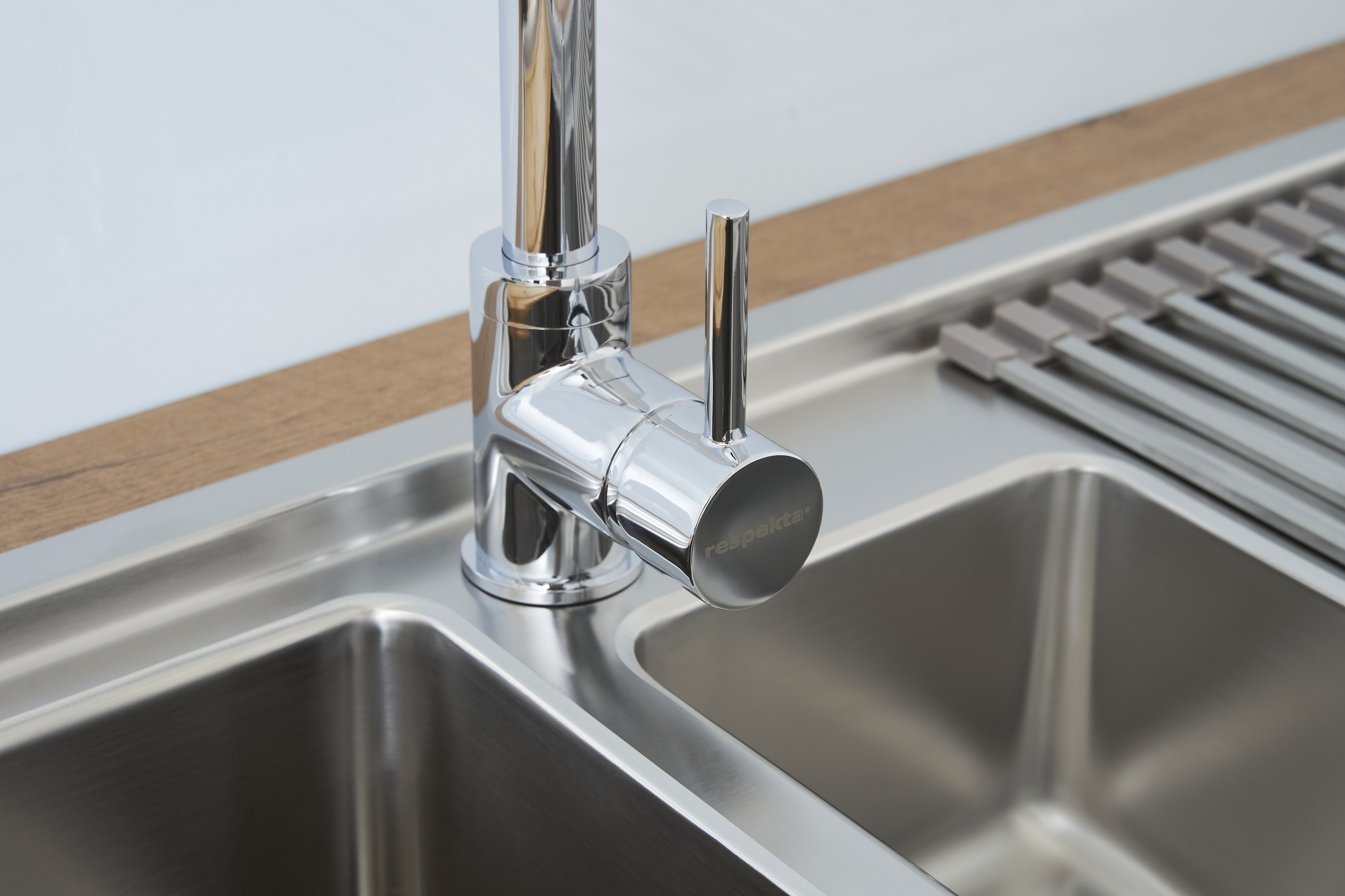 Eine verchromte Armatur über einem Edelstahlbecken. Der Wasserhahn hat einen Hebel und das Wort 'respekta' ist sichtbar.