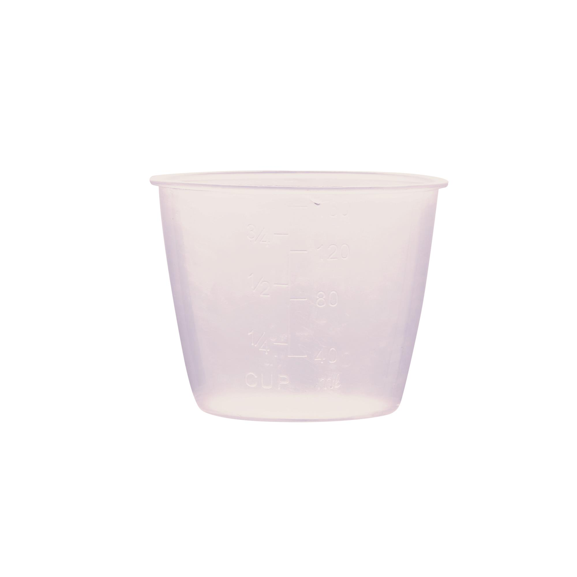Una taza medidora transparente de plástico con marcas de ml y taza. Está sobre un fondo blanco.