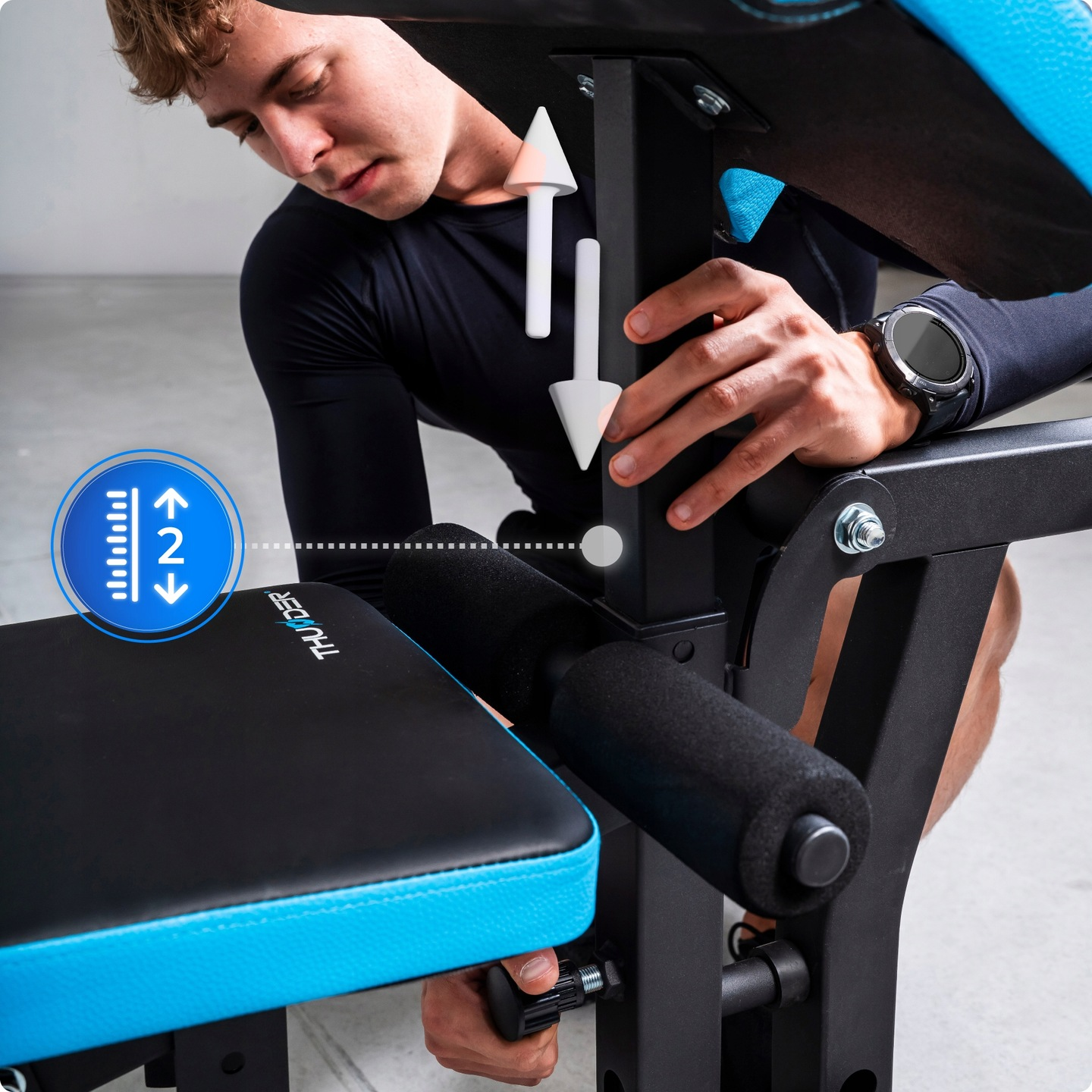 Mężczyzna reguluje ławkę do ćwiczeń. Strzałki wskazują kierunek regulacji. Ławka ma czarną i niebieską wyściółkę.