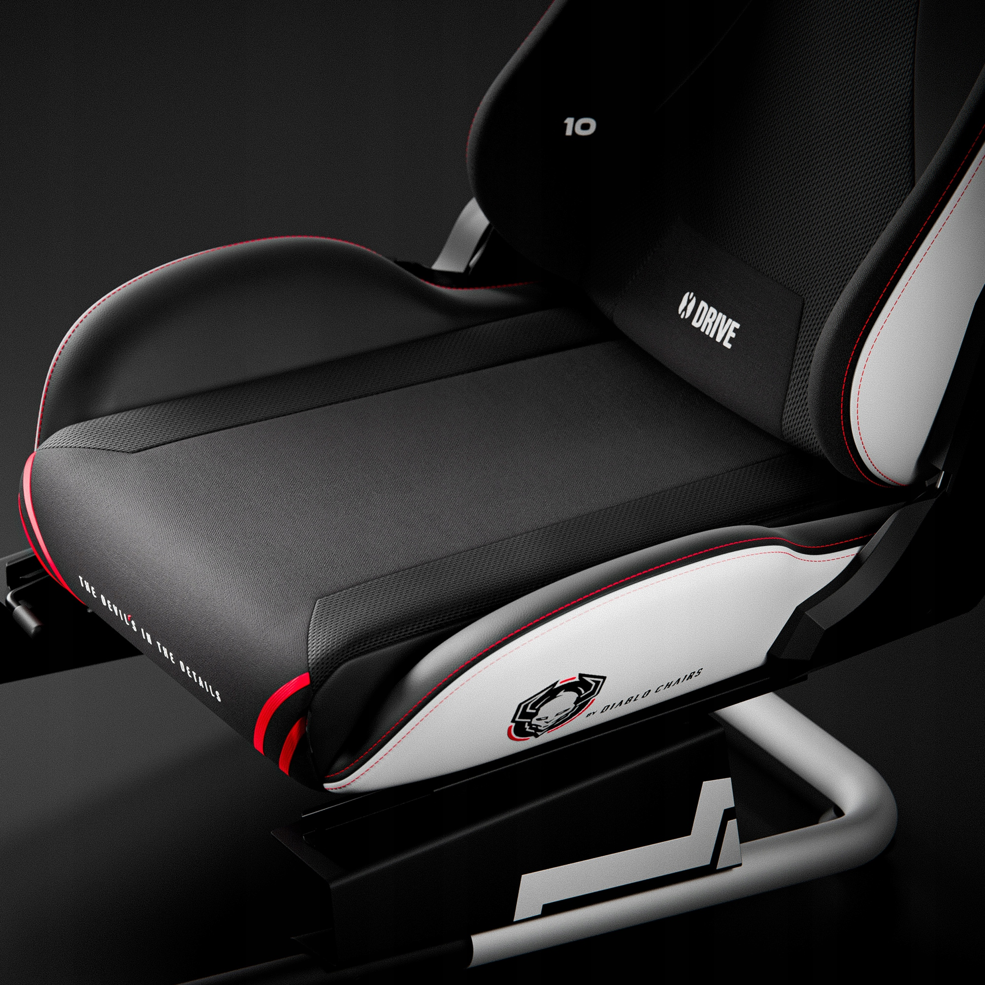 Krzesło do gier z czarnym siedziskiem, białymi akcentami i czerwonymi szwami. Zawiera markę 'DRIVE' i 'DIABLO CHAIRS'.