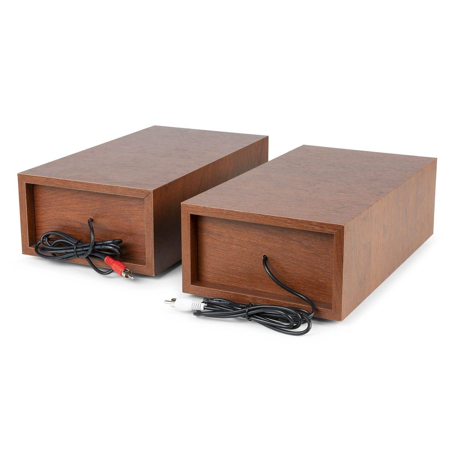 Two wooden speakers sit side by side. Cables with red and white connectors extend from the back.