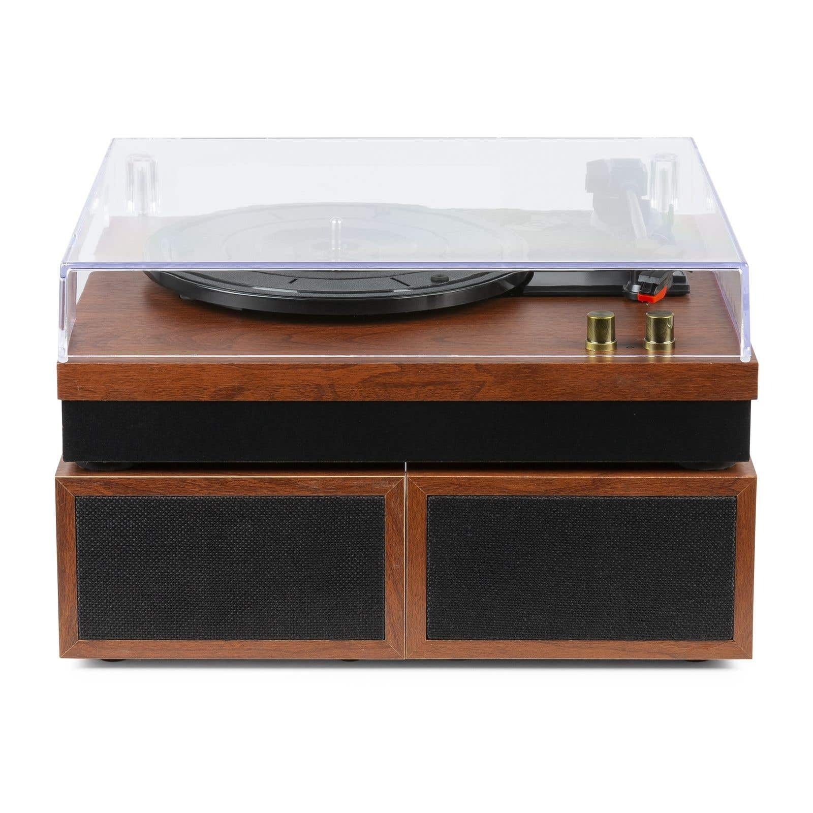A turntable with a clear cover sits on a wooden base with speakers. Gold knobs are visible.