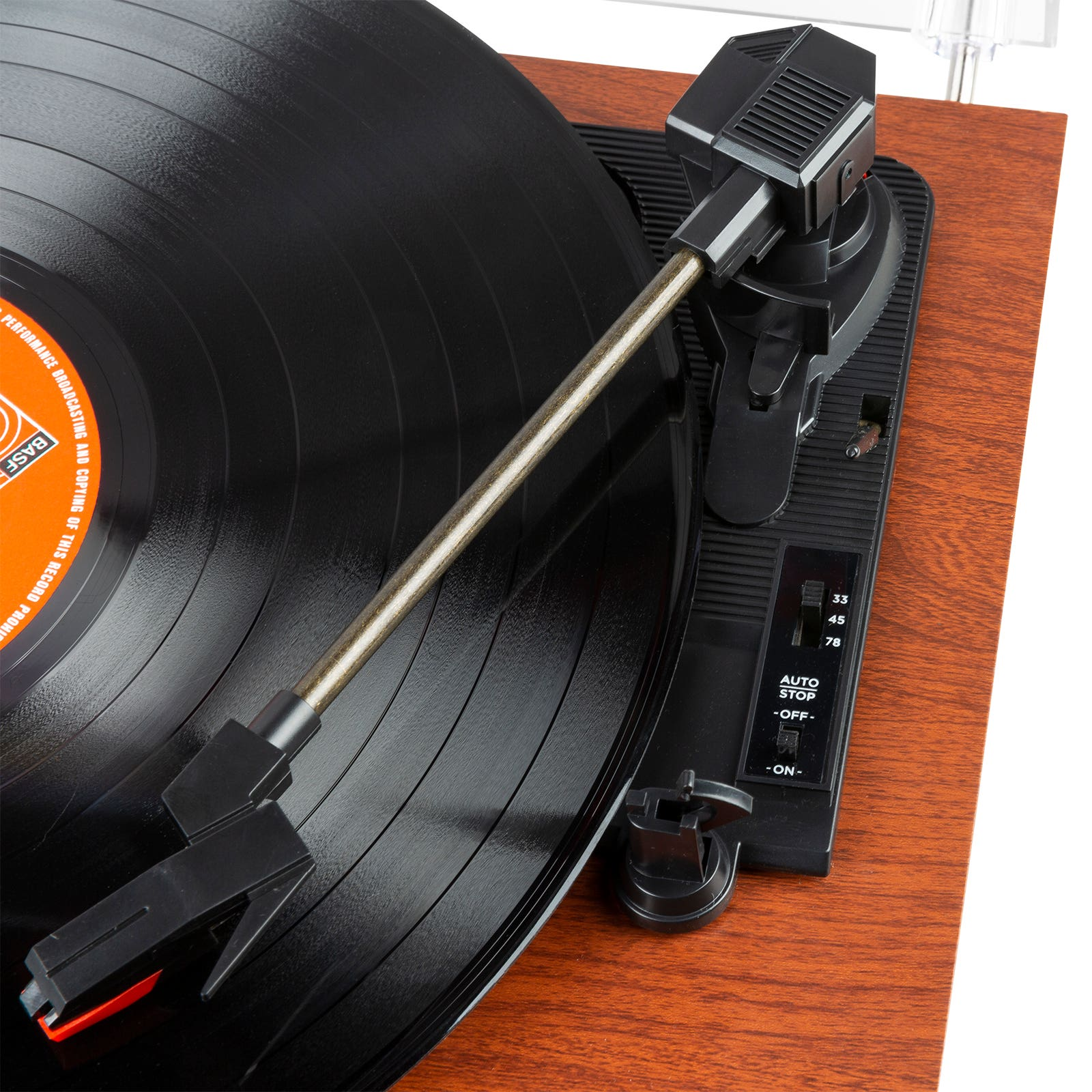A turntable with a black record playing. The tone arm is over the record. Brown wood base.