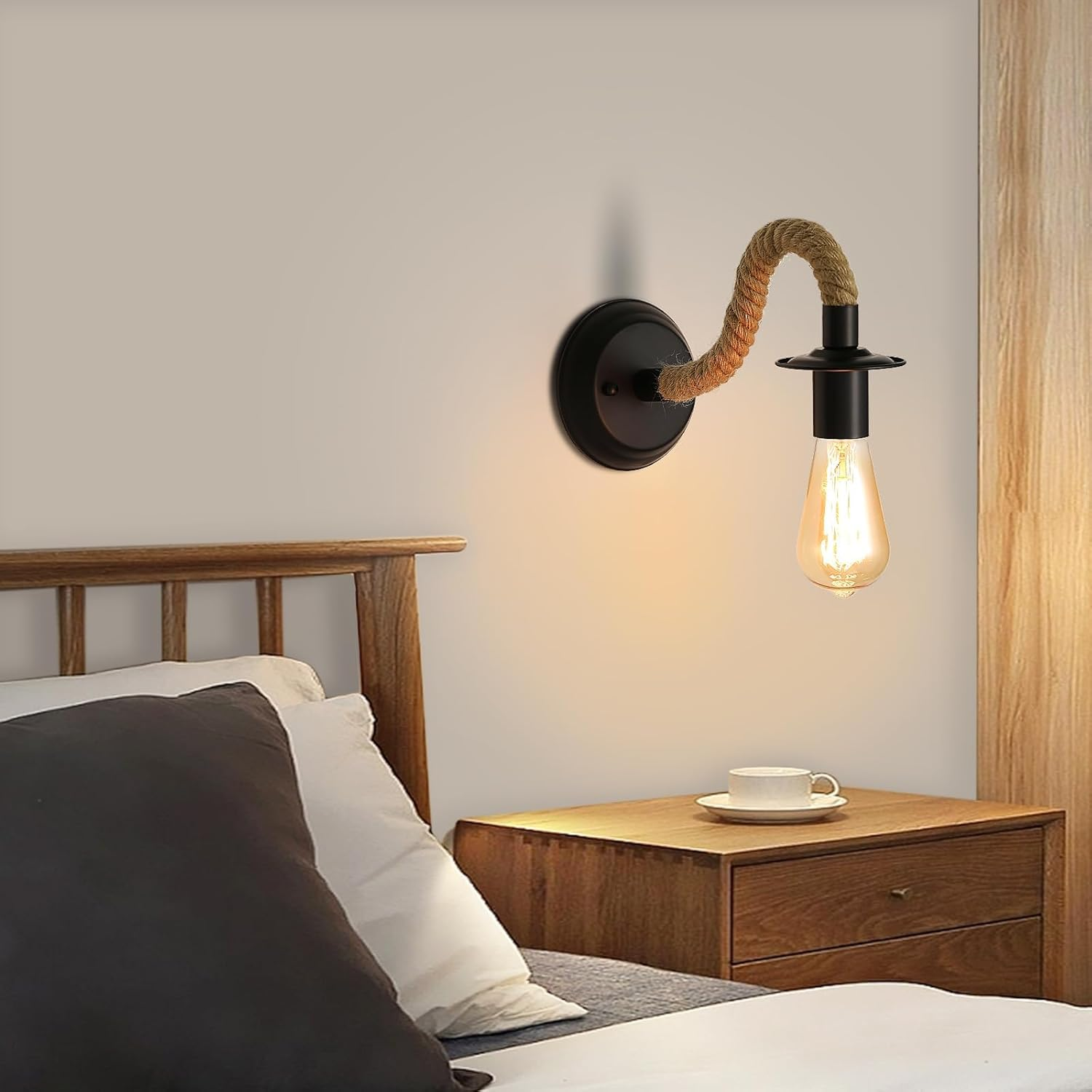Schlafzimmer mit Wandlampe, Bett und Nachttisch. Die Lampe hat ein Seil-Design. Auf dem Nachttisch stehen eine Tasse und Untertasse.