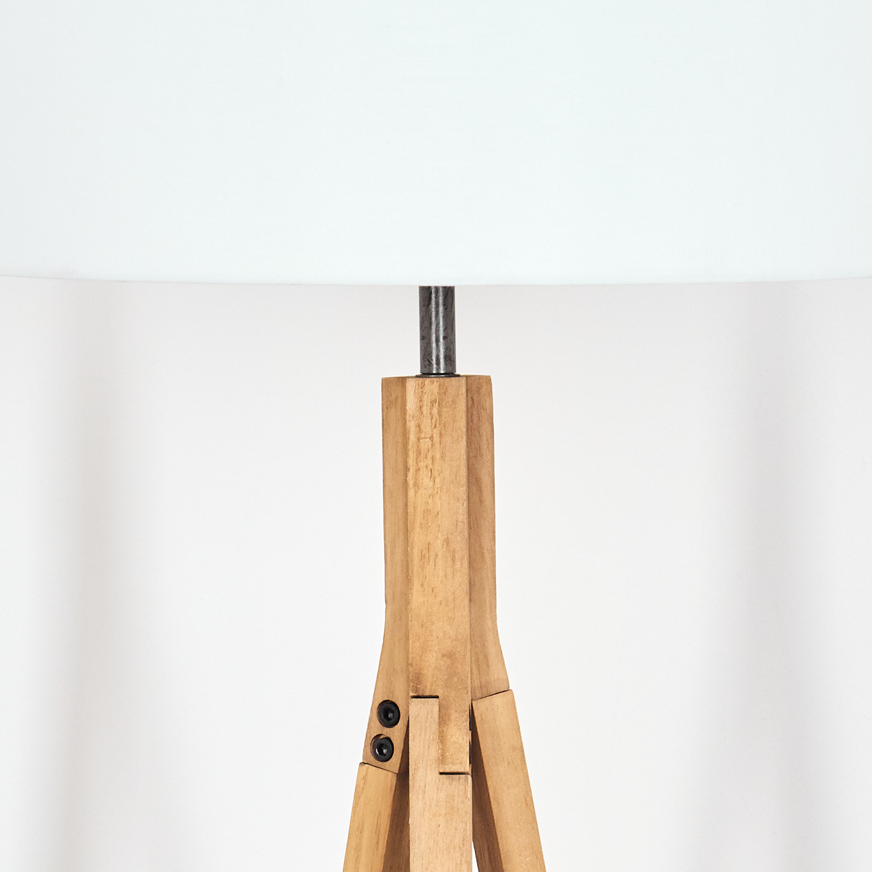Eine Holz-Dreibein-Lampe mit weißem Lampenschirm. Die Lampe steht auf weißem Hintergrund. Die Lampe ist aus Holz.