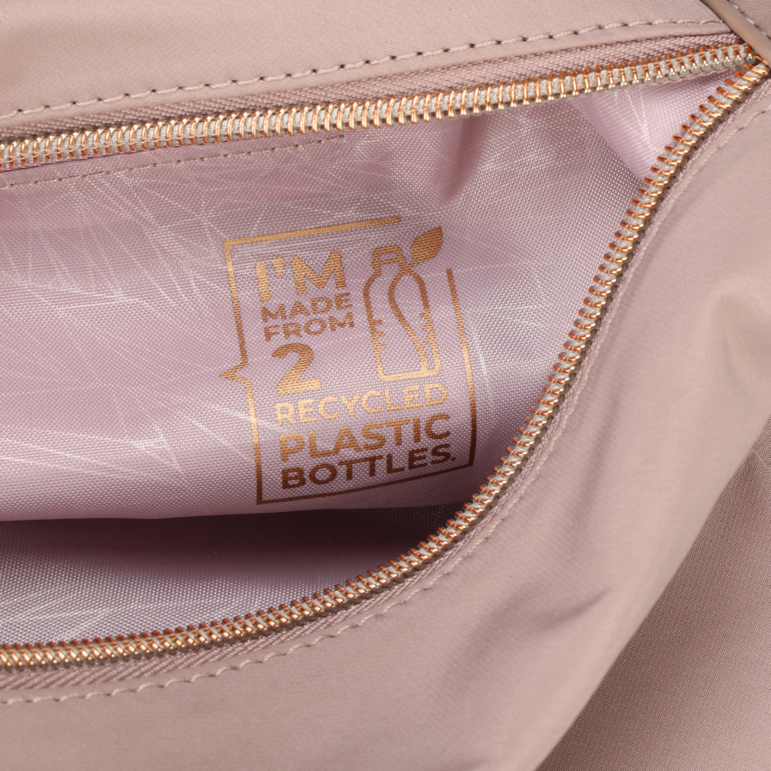 Primo piano dell'interno di una borsa rosa con cerniera dorata. Il testo recita: Realizzato con 2 bottiglie di plastica riciclate.