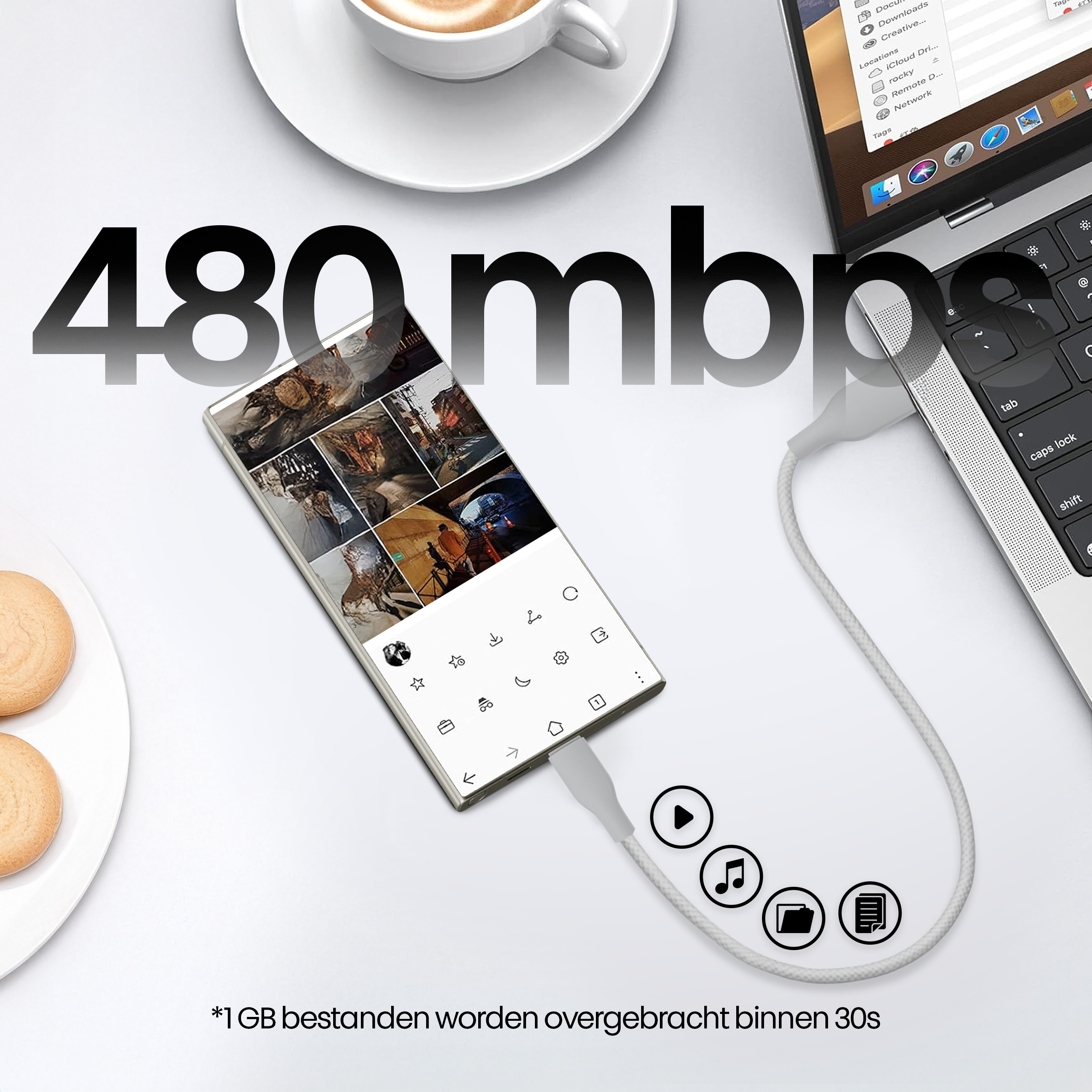 Een telefoon aangesloten op een laptop met een witte kabel. Een kopje koffie en koekjes links.