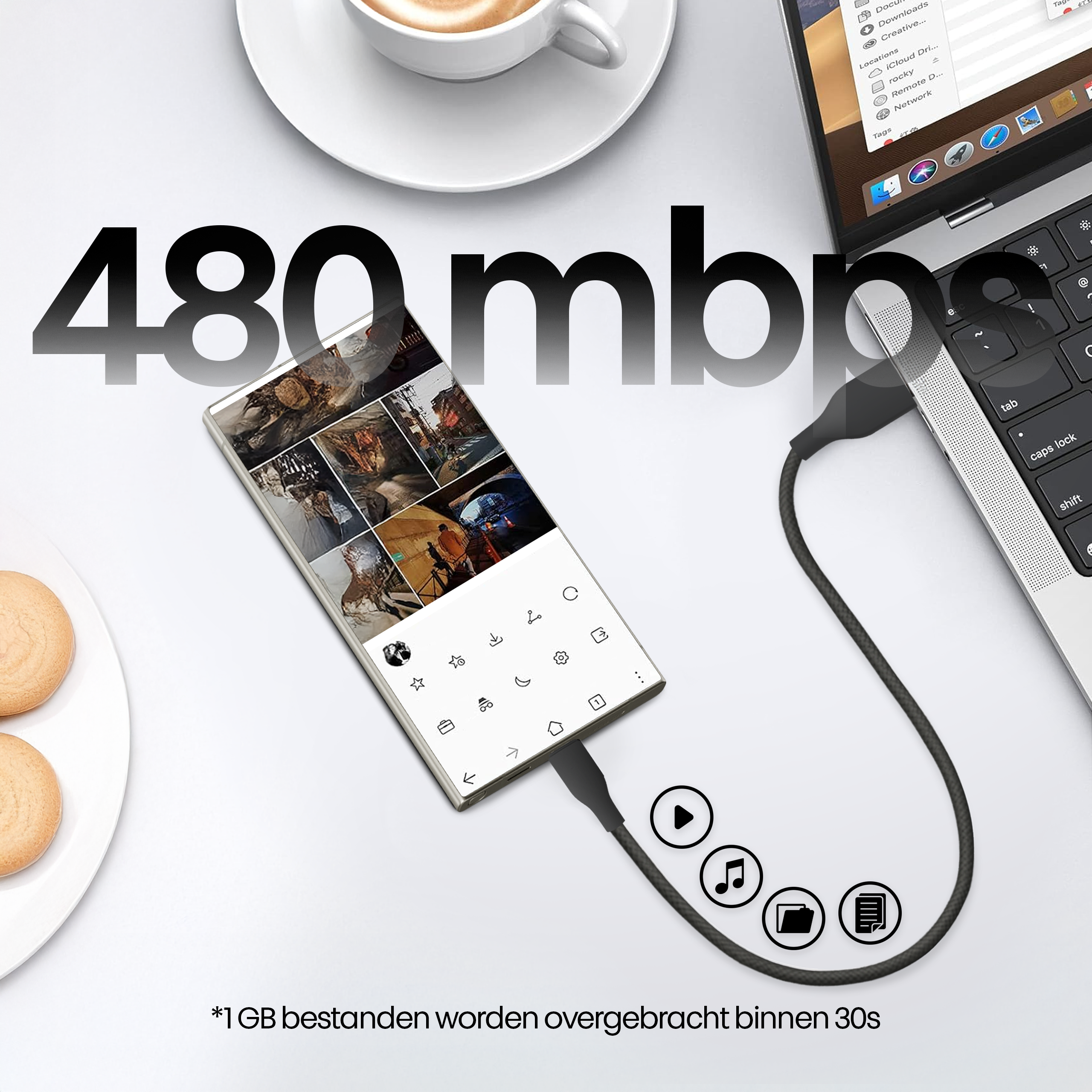 Een telefoon verbonden met een laptop met een kabel. Een kop koffie en twee koekjes op tafel.