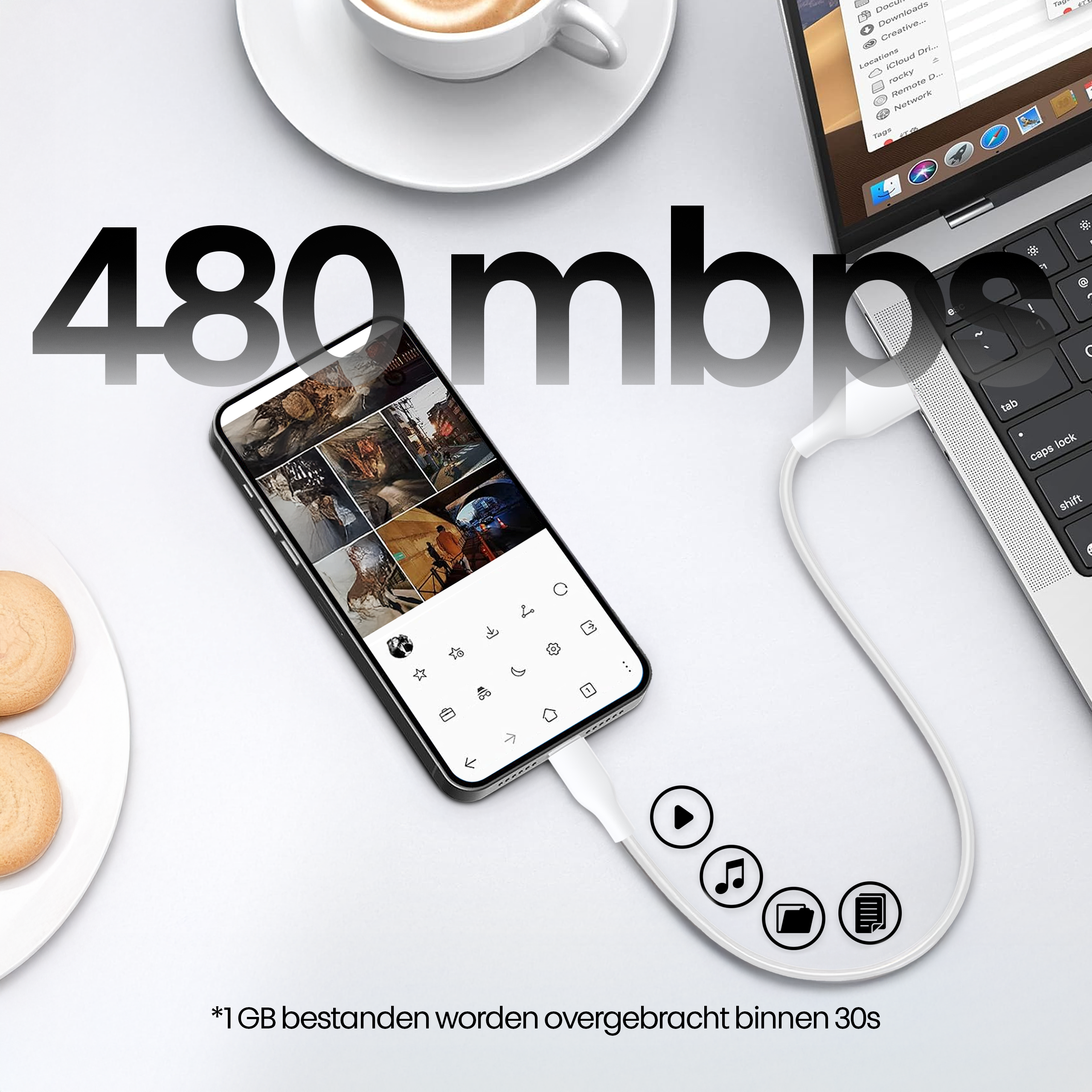 A phone is connected to a laptop with a white cable. A coffee cup and cookies are on the side. The text says 480mb.