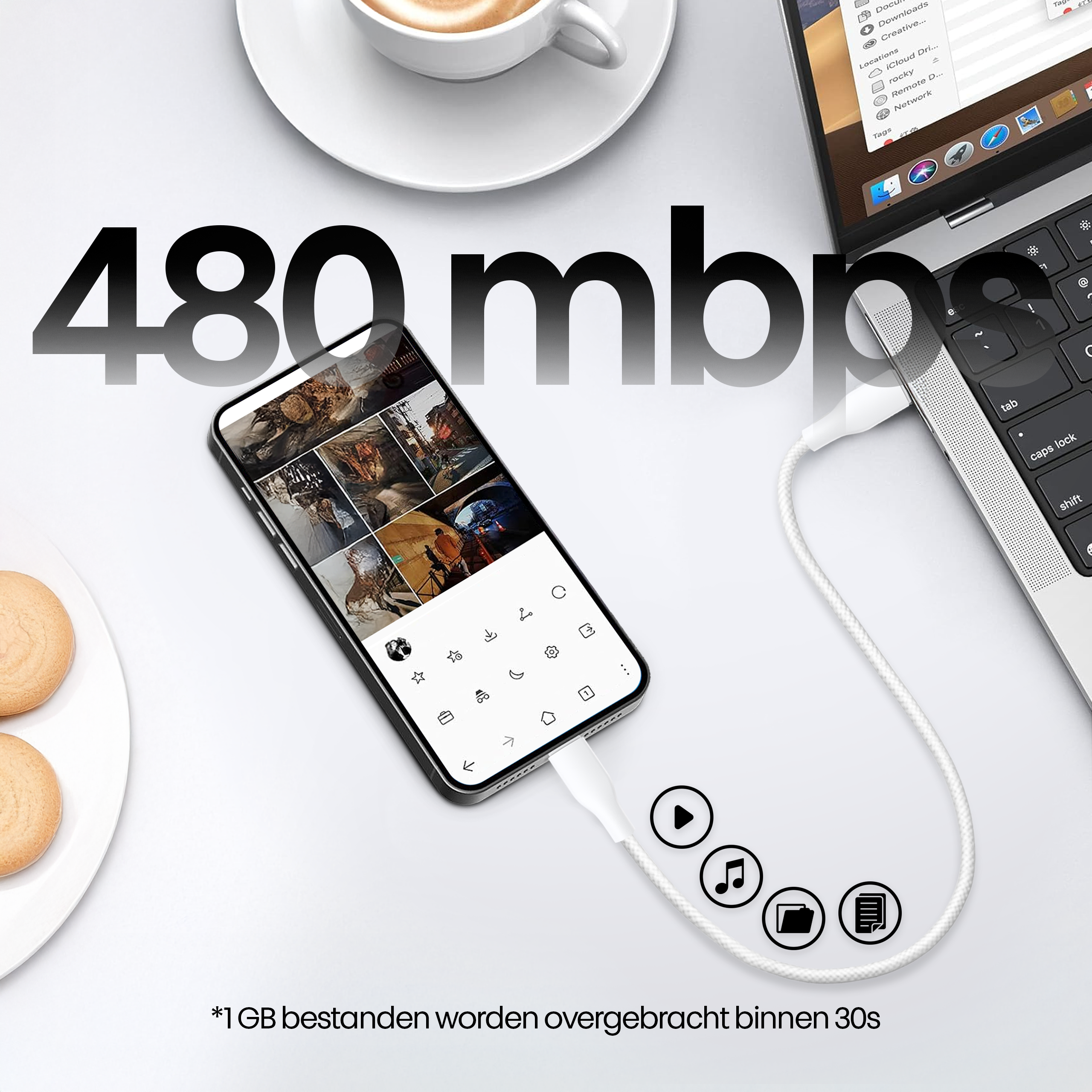 Een telefoon verbonden met een laptop via een witte kabel. Er is een kopje koffie en een bord met brood.