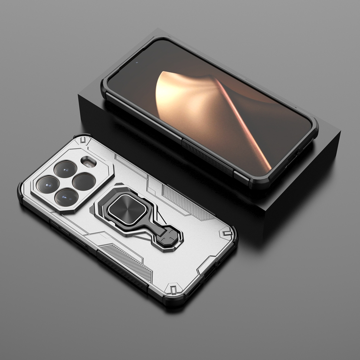 Twee telefoonhoesjes. Eén zilver met een ringhouder, de andere zwart. Beide op een zwart oppervlak.