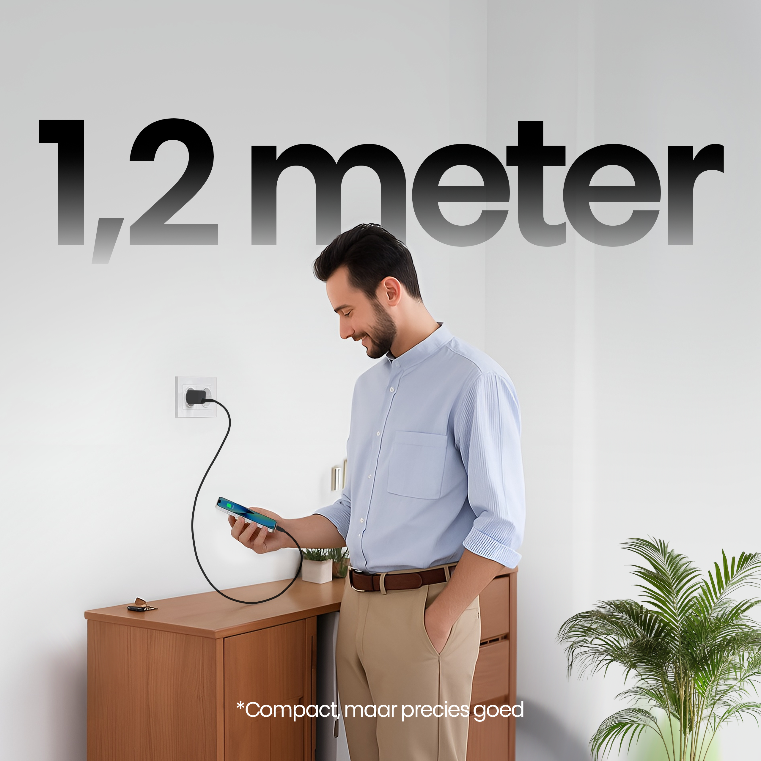 Een man laadt zijn telefoon op met een zwarte kabel. Tekst: '1,2 meter' op een witte muur. Bruine kast.