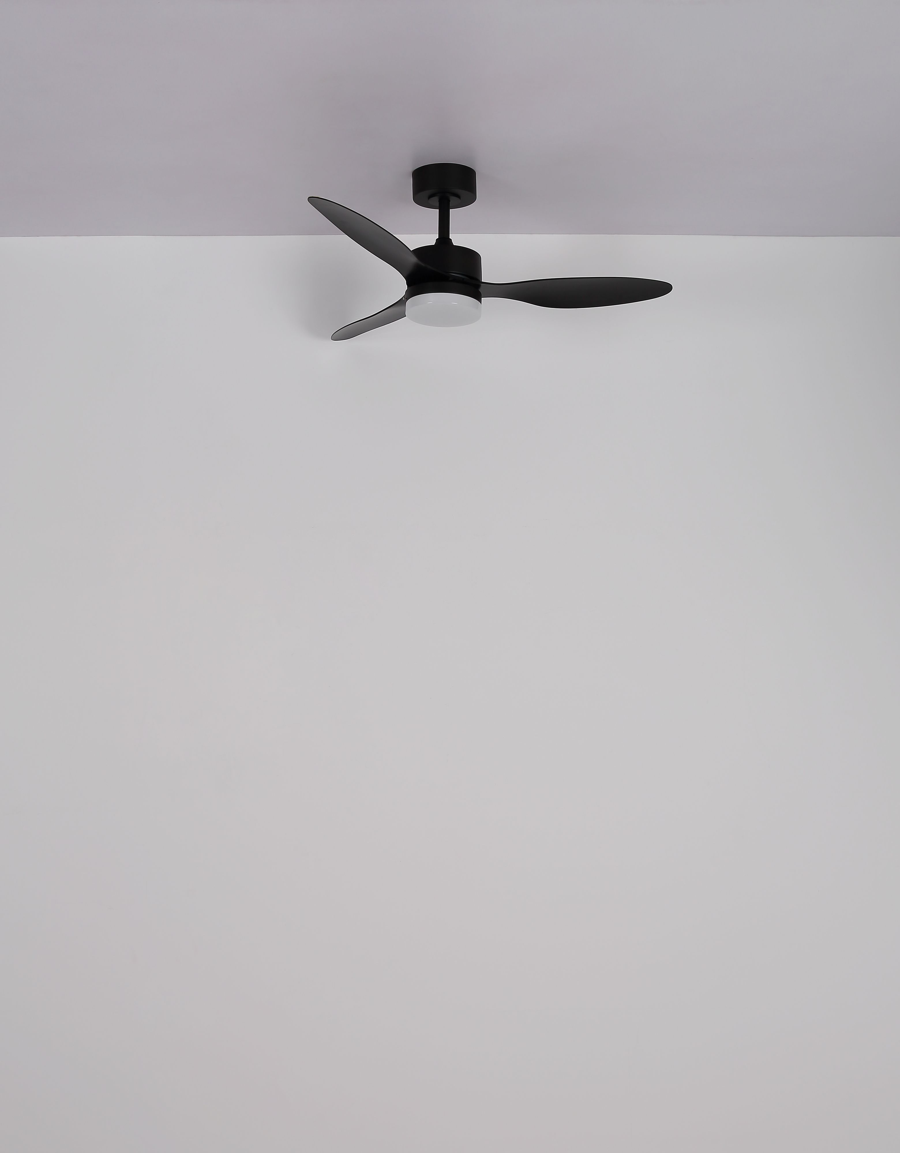 Ein schwarzer Deckenventilator mit drei Flügeln ist an einer weißen Decke montiert. Der Hintergrund ist weiß.