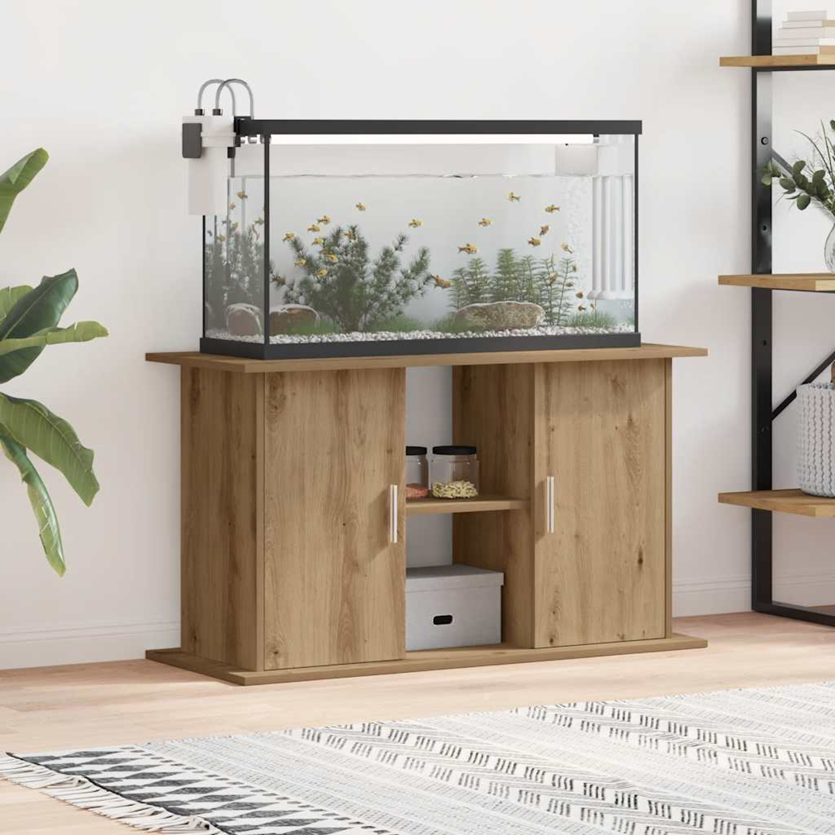 Ein Aquarium steht auf einem Holzschrank. Das Becken hat Pflanzen und Fische. Der Schrank hat Türen und Regale mit Gläsern und einer Box.