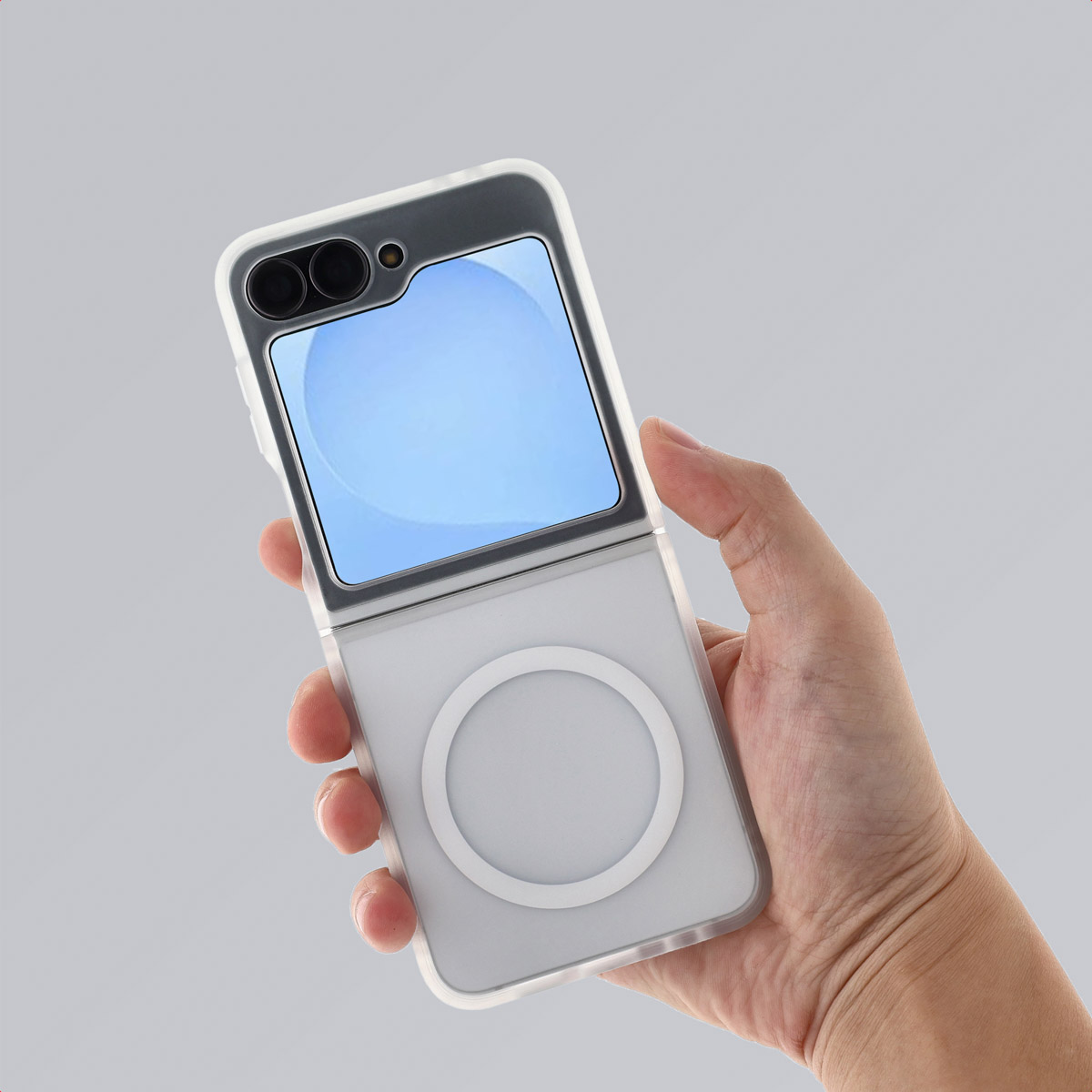 Een hand houdt een witte en doorzichtige telefoonhoes vast met een opvouwbare telefoon erin. De telefoon heeft een blauw scherm en een witte cirkel.