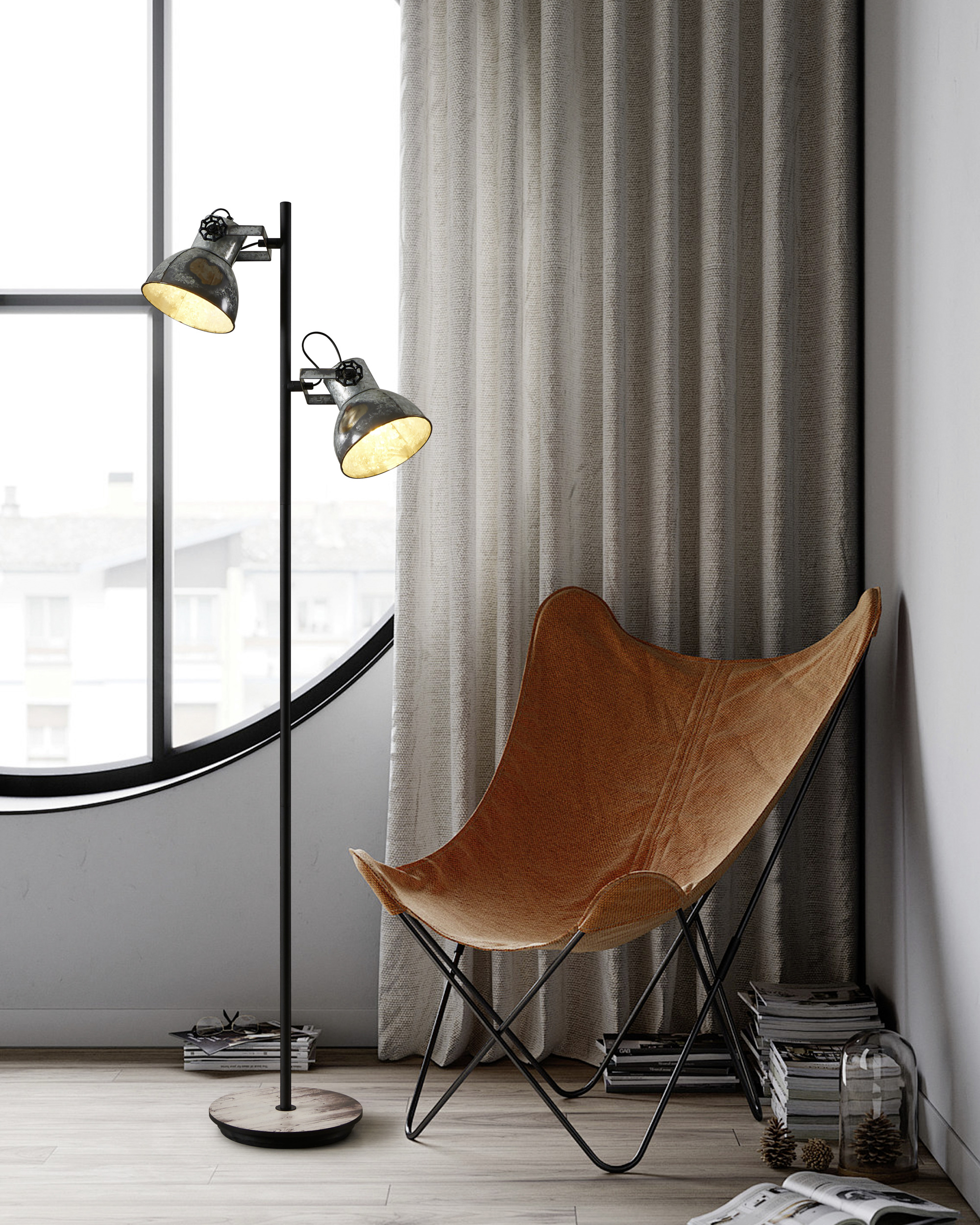 Ein Raum mit einer Stehlampe, einem Schmetterlingsstuhl und einem gebogenen Fenster. Hellbeige Vorhänge im Hintergrund.