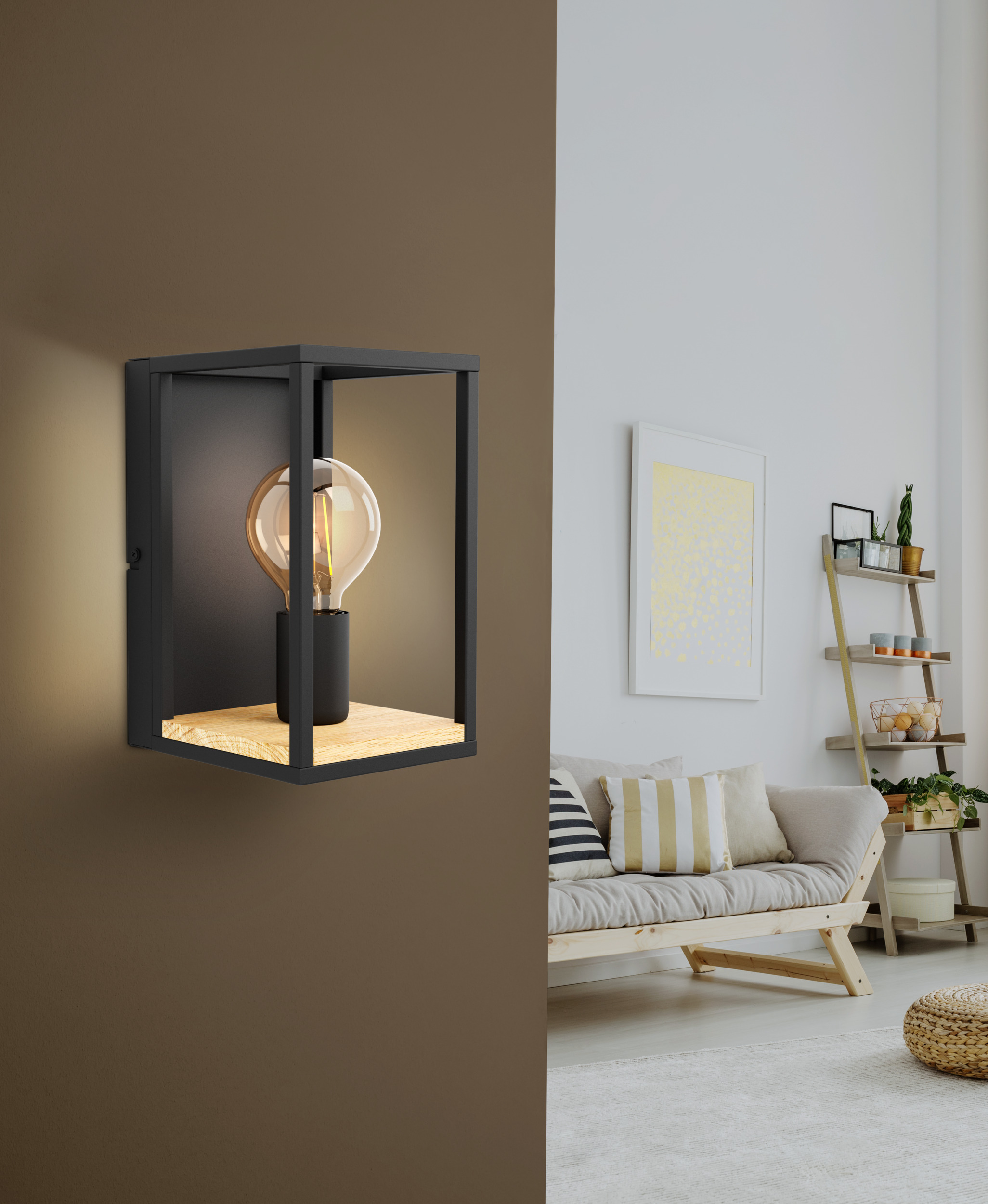 Applique murale noire avec une ampoule. Un canapé, une étagère échelle et un tapis en arrière-plan.