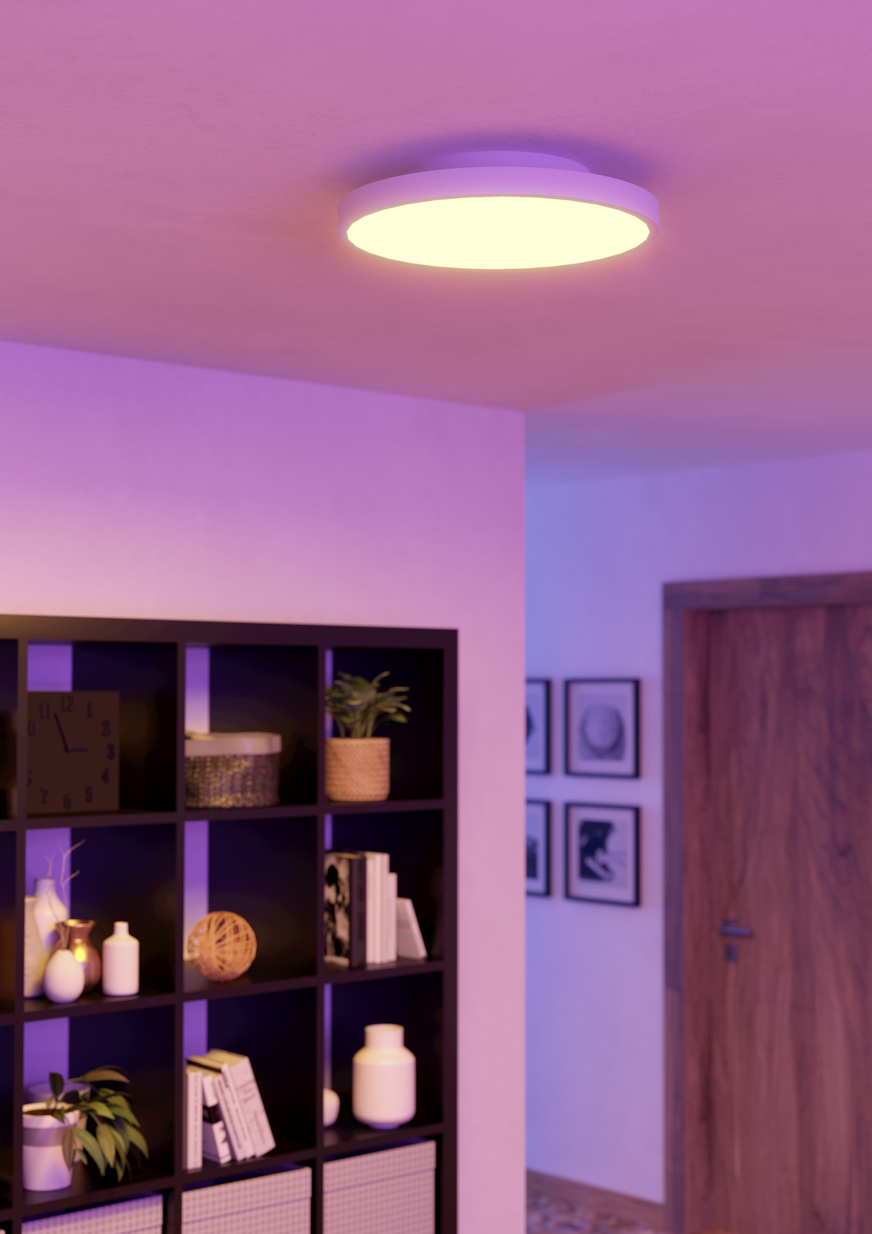 Una stanza con una luce a soffitto. Una mensola nera ha delle decorazioni. Una porta è a destra. Le pareti sono viola.