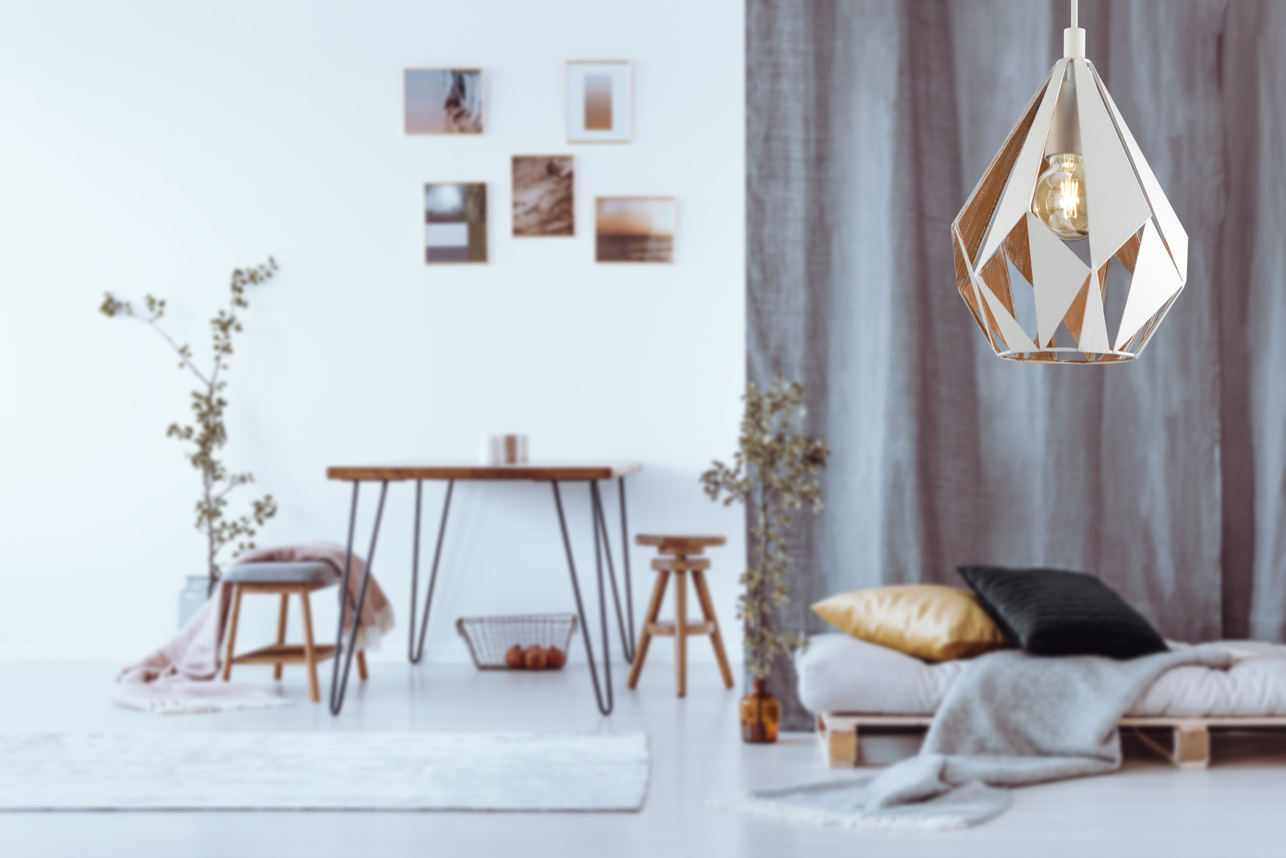 Una stanza moderna con lampada geometrica, tavolo e letto. Le decorazioni includono piante e quadri.